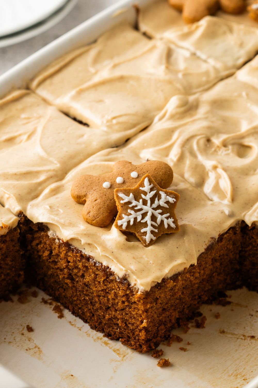 Gingerbread Cake with Cream Cheese Frosting in pan with sliced cake in it and cookies
