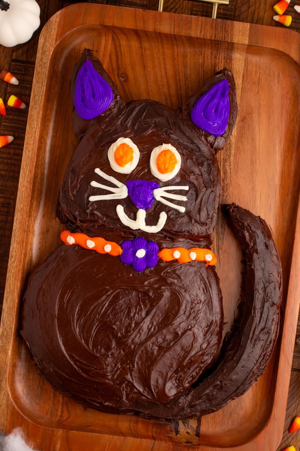 side view of Easy Halloween Black Cat Cut Out Cake on a serving tray with candy corn around it 