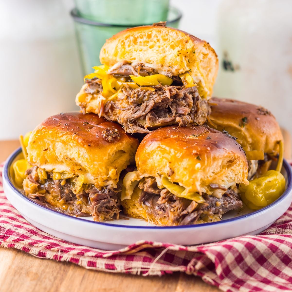 Slow Cooker Mississippi Pot Roast Sliders stacked on a plate sitting on a table 