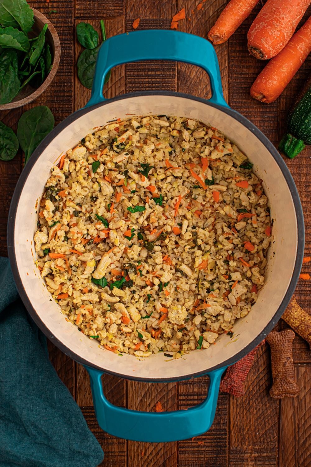 Homemade Turkey and Rice Dog Food with Veggies in a stock pot sitting on table with ingredients around table 
