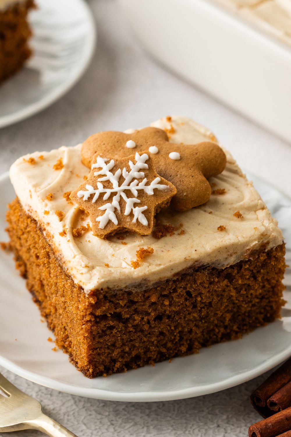 Gingerbread Cake with Cream Cheese Frosting sliced and placed on plate with cookies on top for decoration