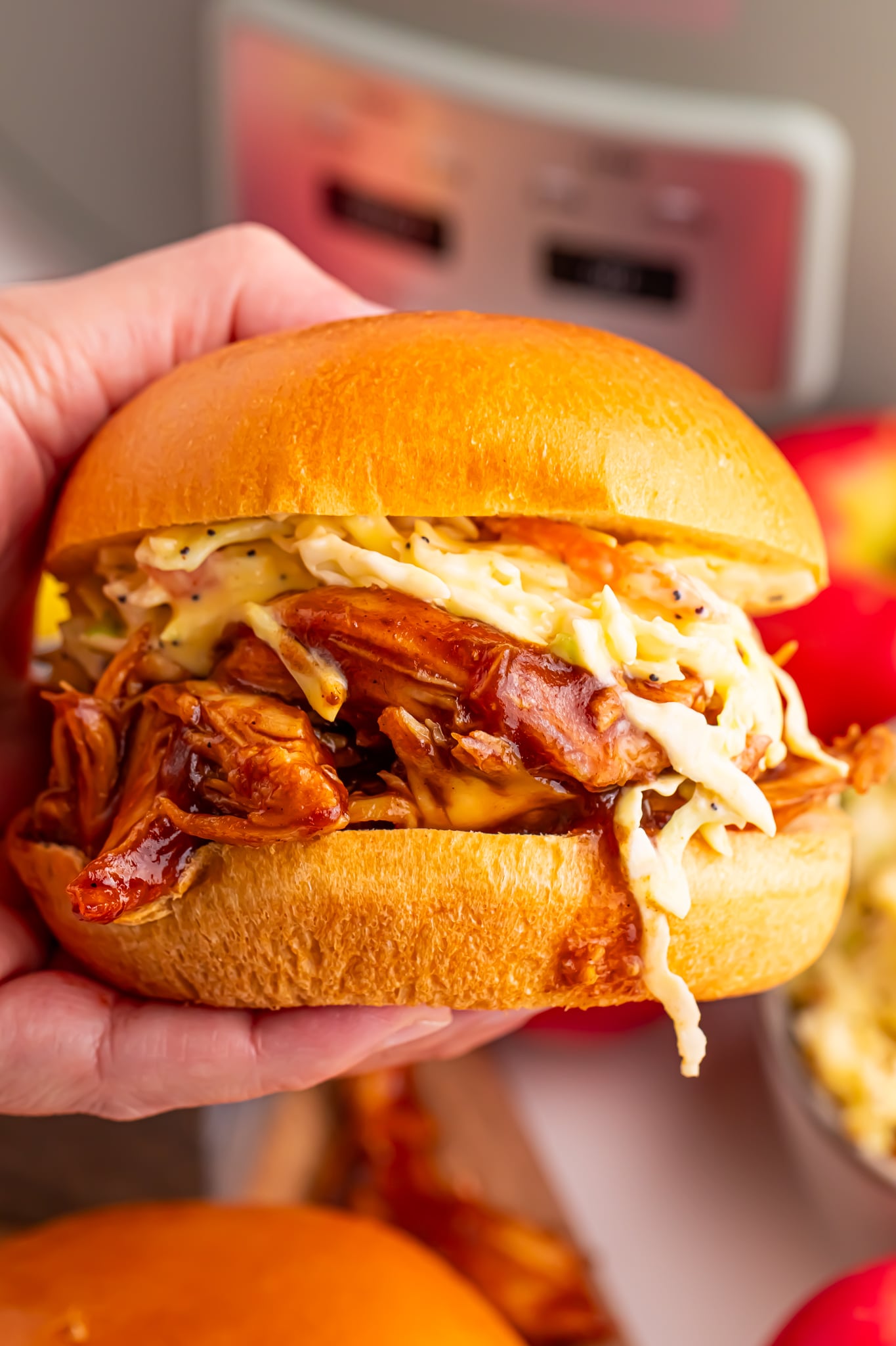 hand holding a sandwich of the Crockpot Apple Butter BBQ Pulled Chicken