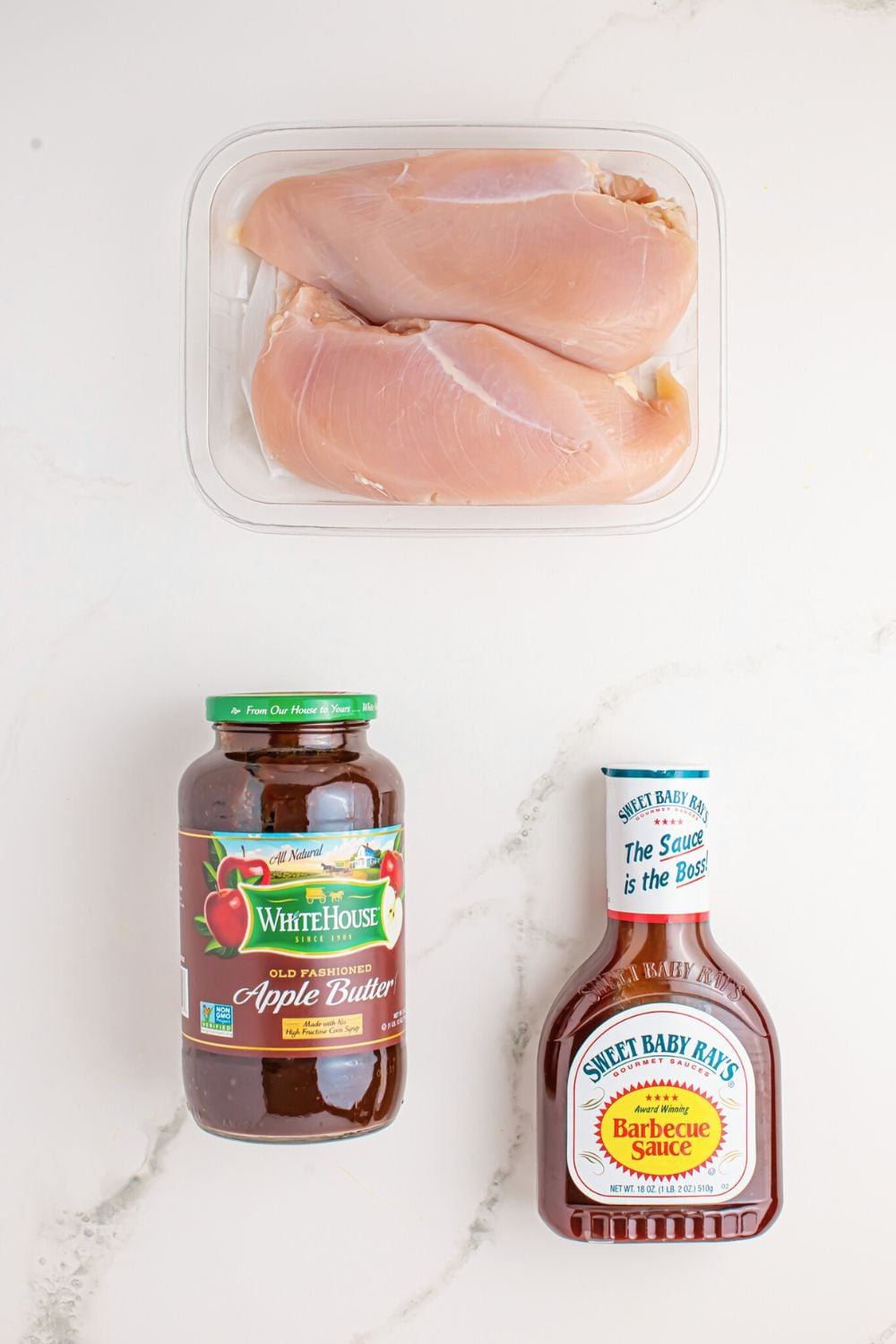 ingredients for Crockpot Apple Butter BBQ Pulled Chicken on table in jars and container of chicken