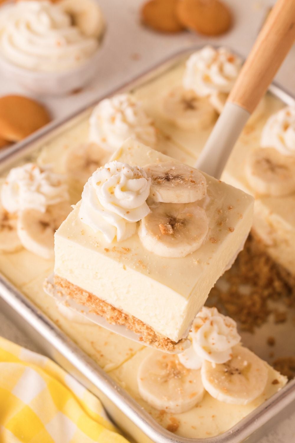 No Bake Banana Pudding Cheesecake Bars in a pan with one being lifted out of the pan with a spatula
