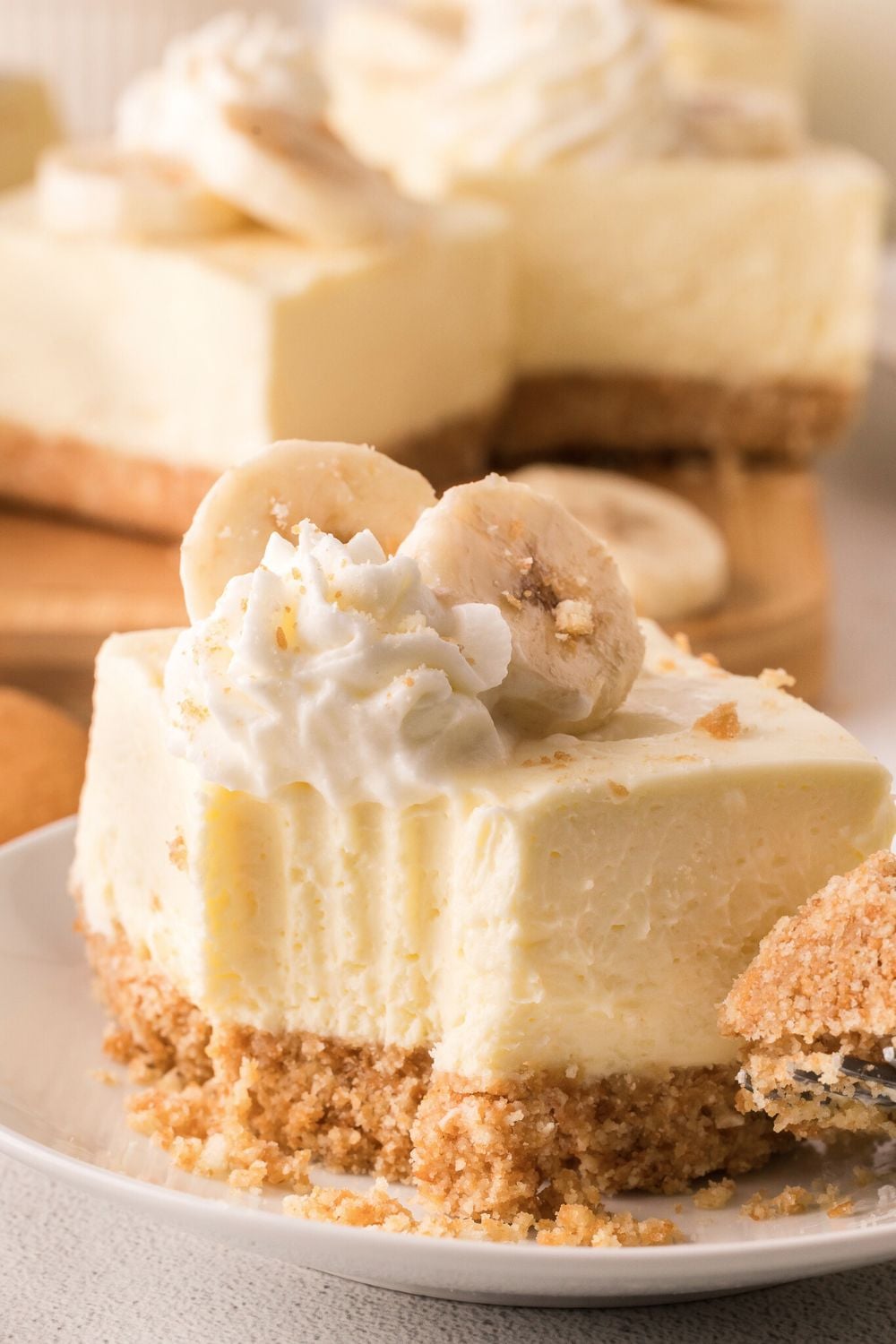 a No Bake Banana Pudding Cheesecake Bar on a plate with one bite taken out of the square