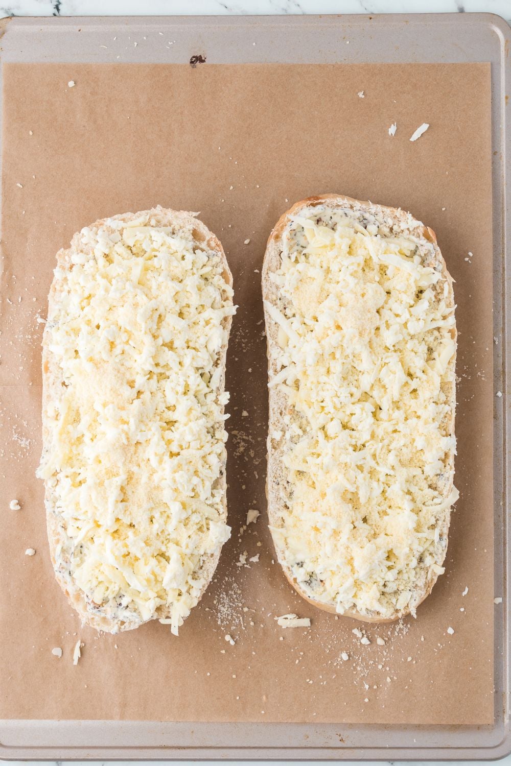 Cheesy Garlic Bread with cheese sprinkled over the top sitting on tray