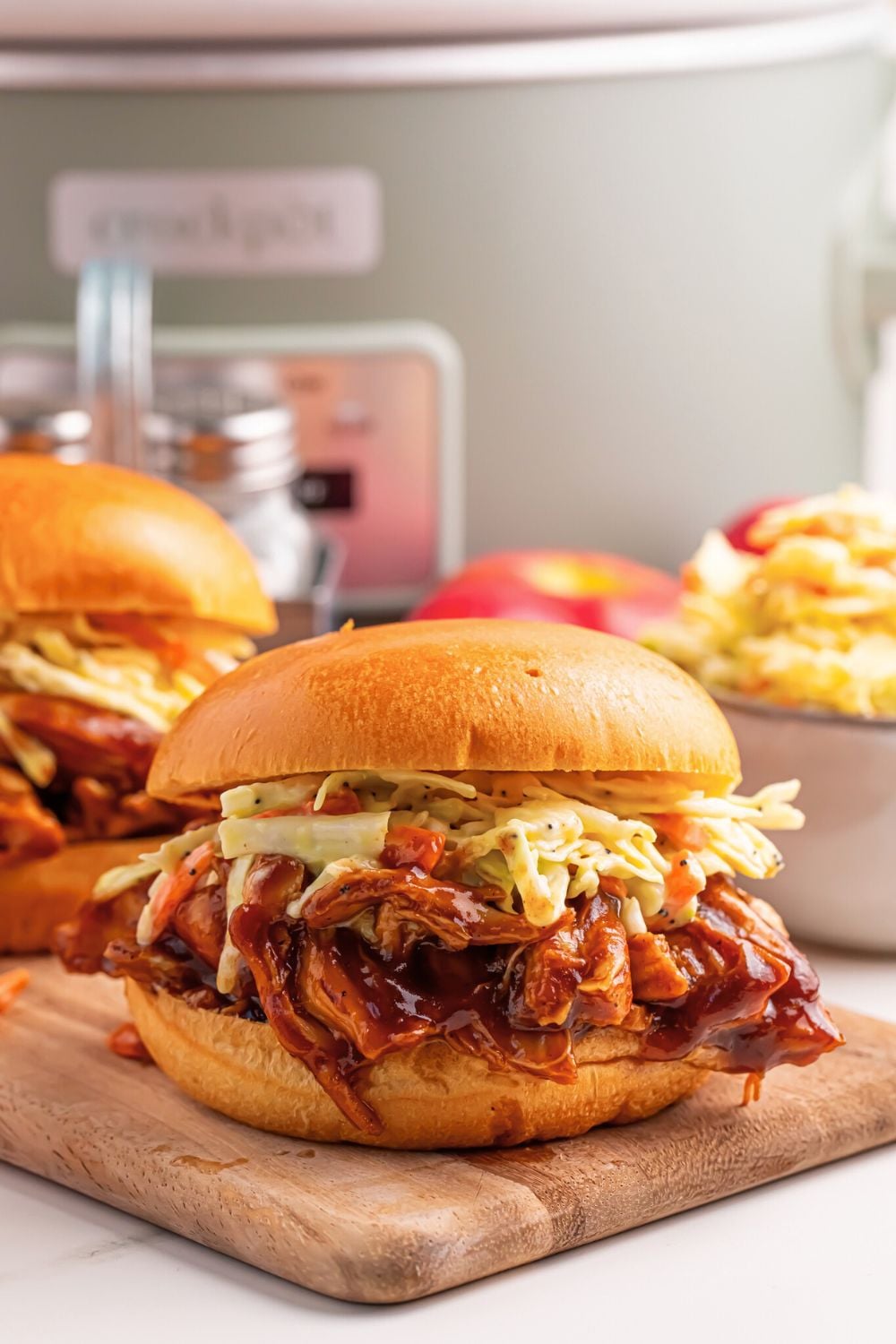 Crockpot Apple Butter BBQ Pulled Chicken sandwiches on table with a bowl of chips to the side