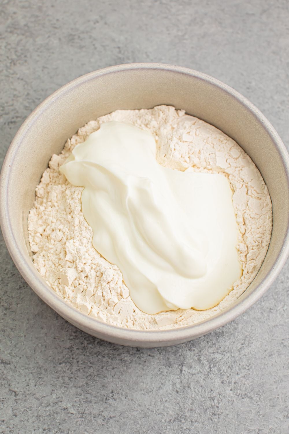 flour and yogurt in a white bowl on table for making 2 Ingredient Dinner Rolls