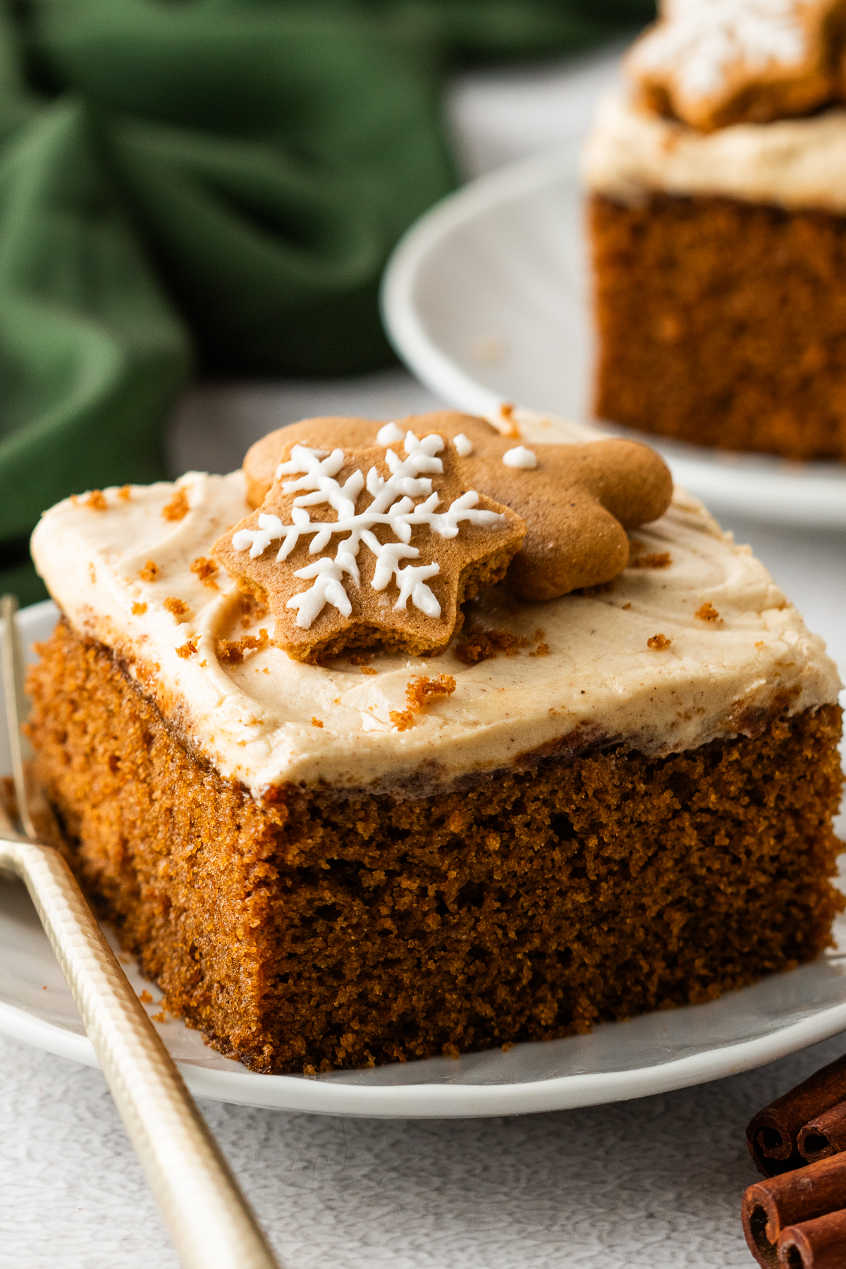 Up close shot of the Gingerbread Cake with Cream Cheese Frosting on white plates with a gold fork next to the slice