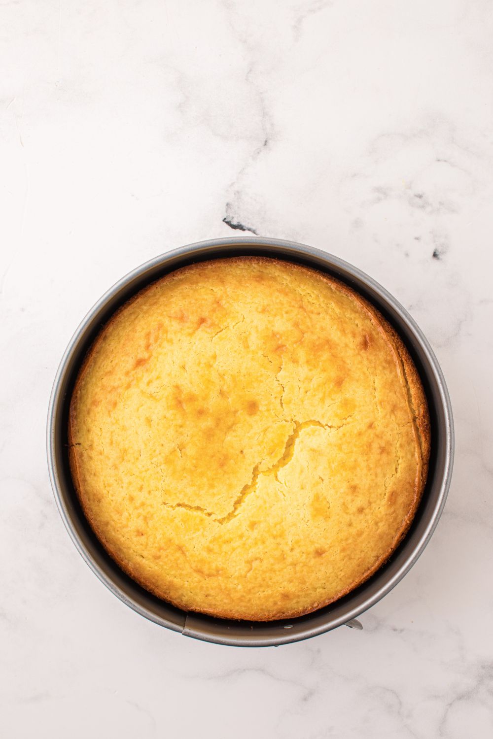 round Lemon Ricotta Cake baked in a pan sitting on a table 