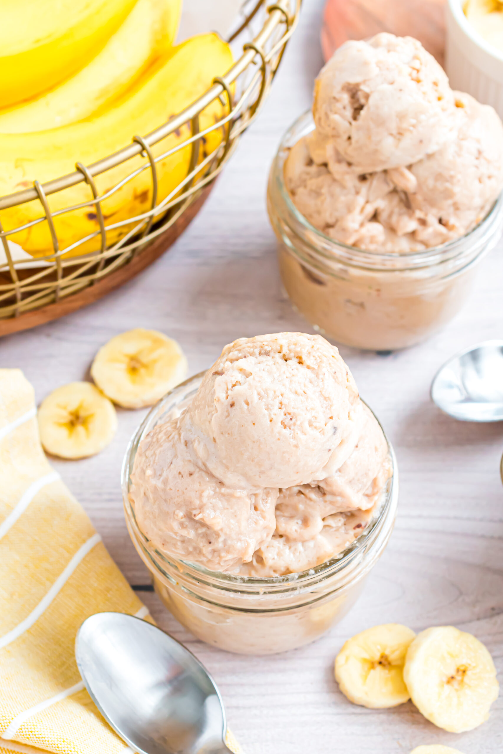 overhead shot of the Banana Ice Cream in a glass bowl on table with slices of bananas around table 