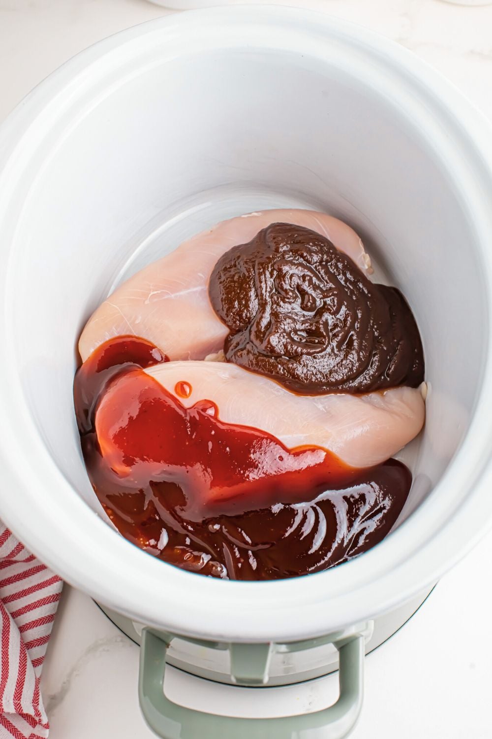 chicken in crockpot with sauce poured over the top for making Crockpot Apple Butter BBQ Pulled Chicken