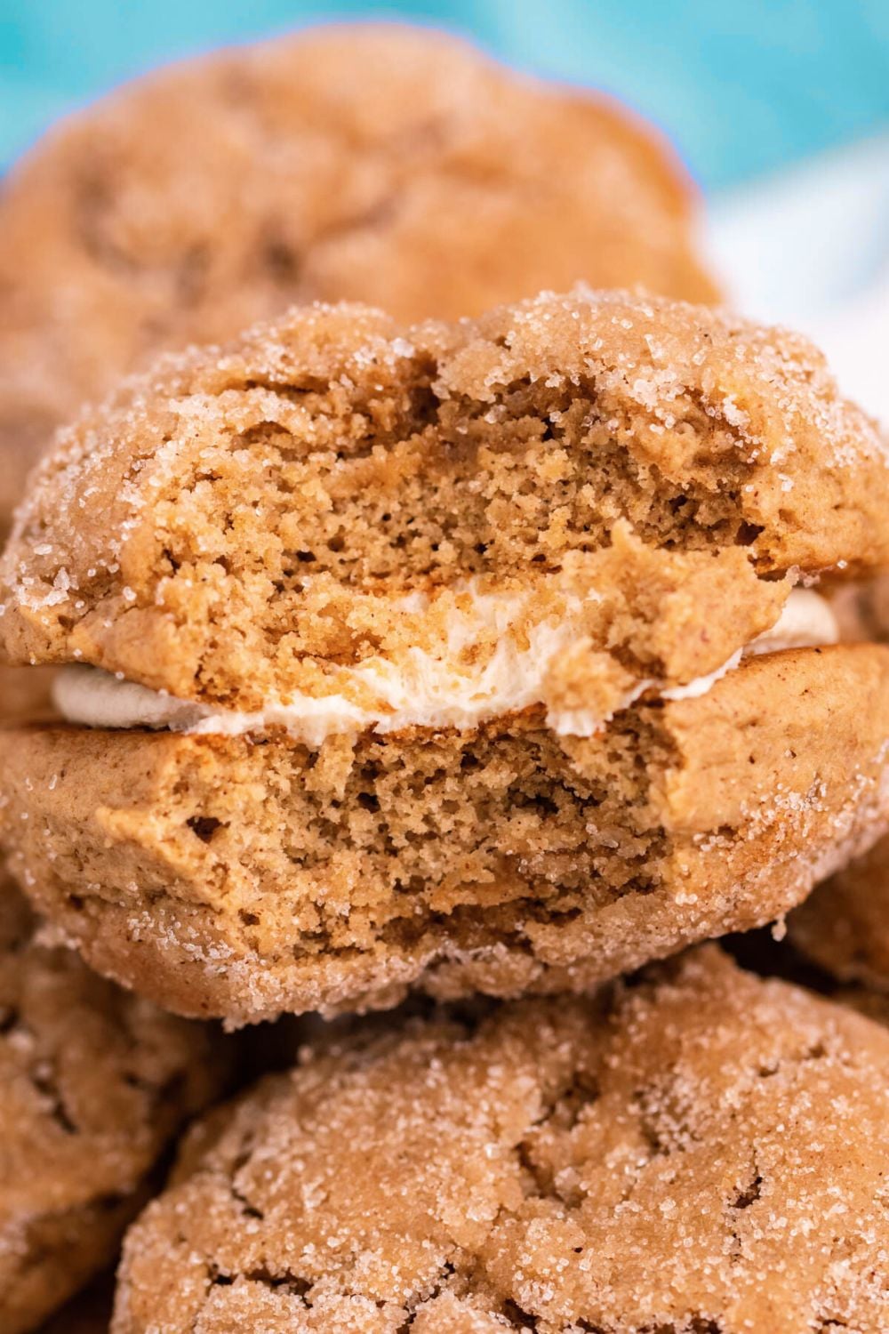 Apple Cider Whoopie Pies stacked on table with one with a bite taken out of it to show how fluffy they are