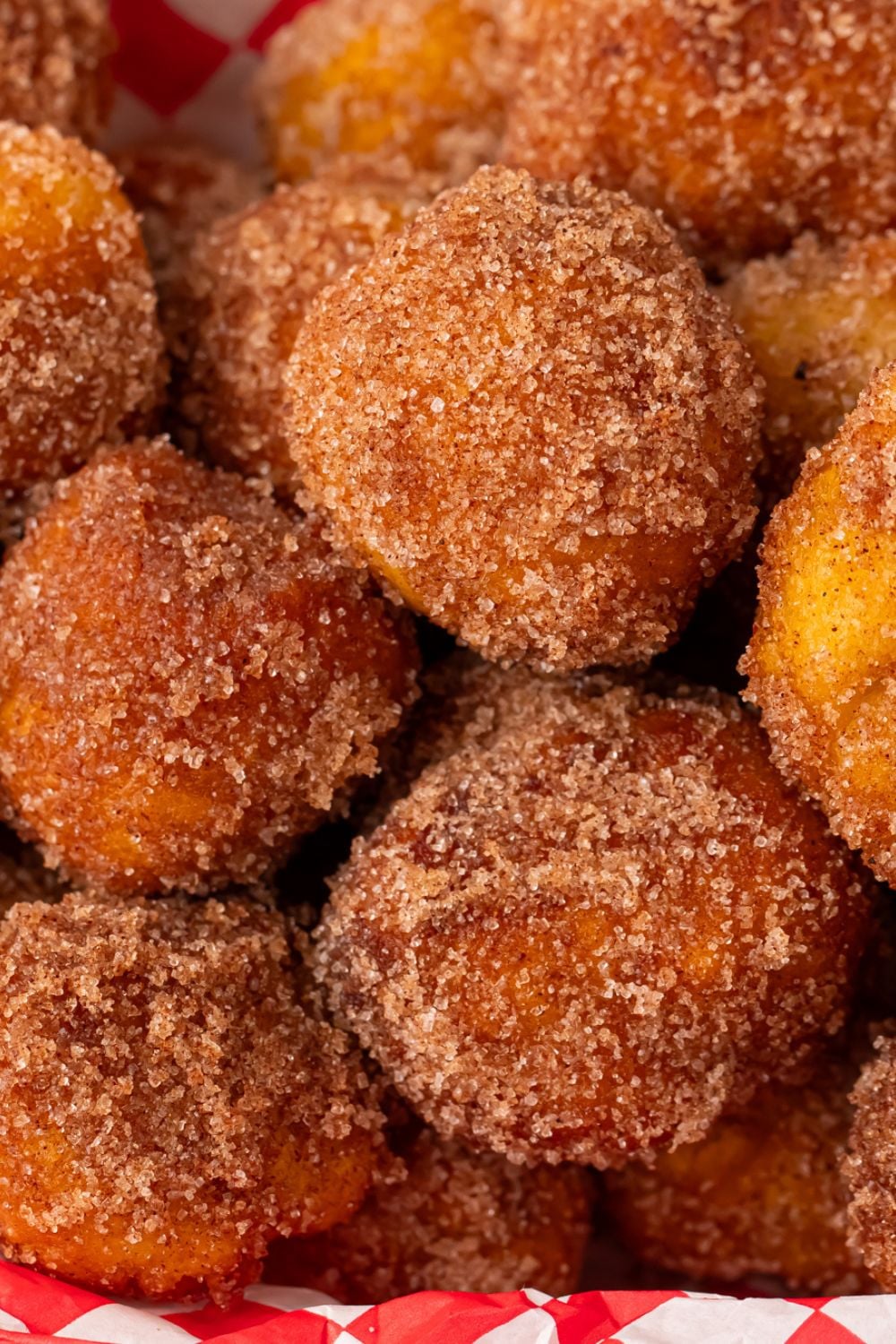 Apple Pie Donut Holes dusted with cinnamon and sugar stacked on top of one another 