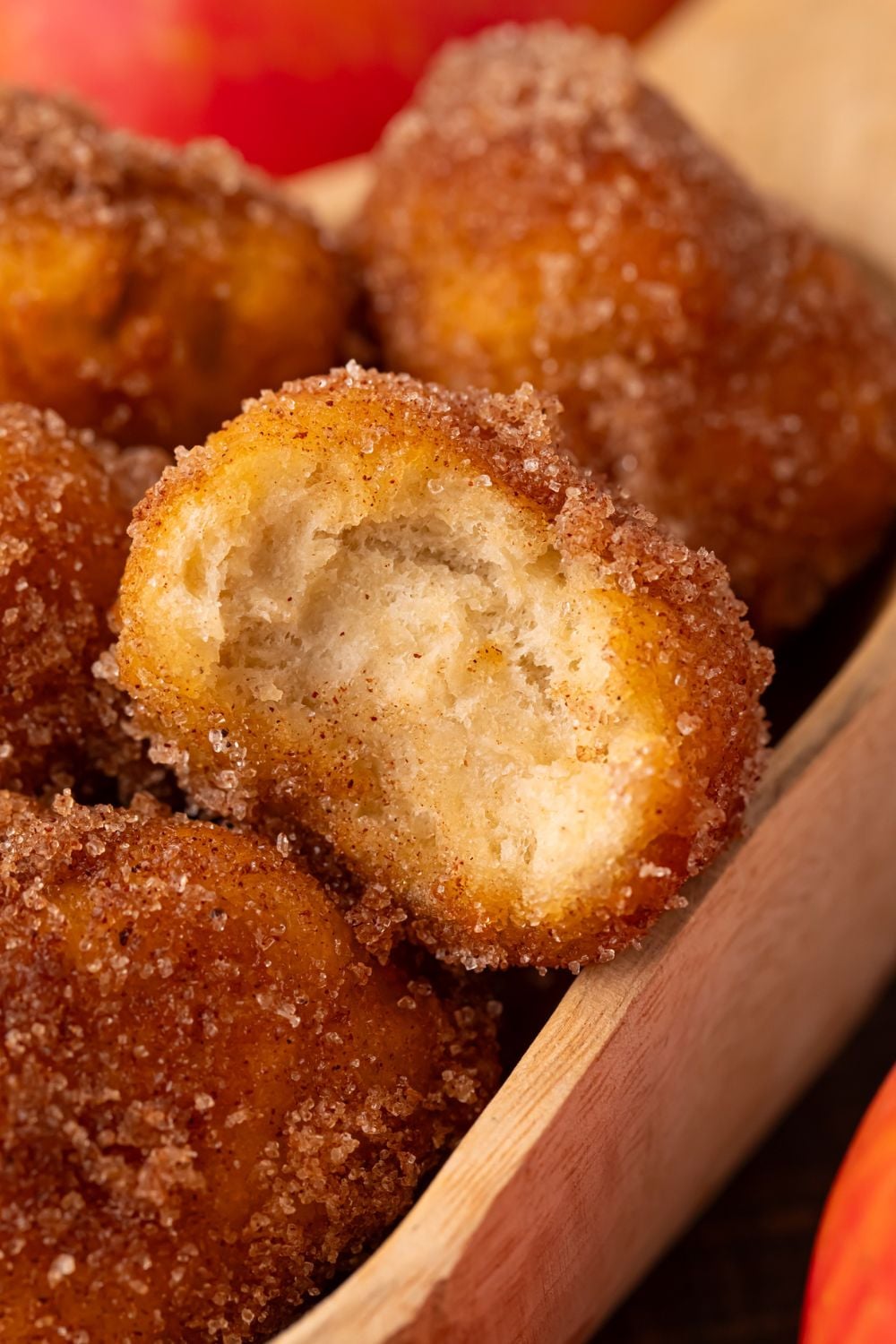 Apple Pie Donut Holes in a wooden spoon with one with a bite taken out of it sitting on top 