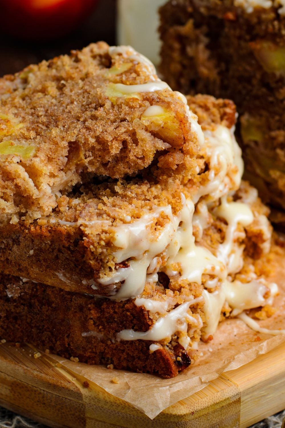 a few slices of Apple Cinnamon Loaf Cake stacked on top of one another with a few bites taken out of the top loaf sitting on a wooden cutting board