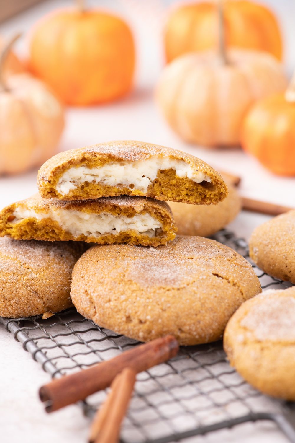 cooling rack on table with a pumpkin cheesecake cookie in center with pumpkins in background