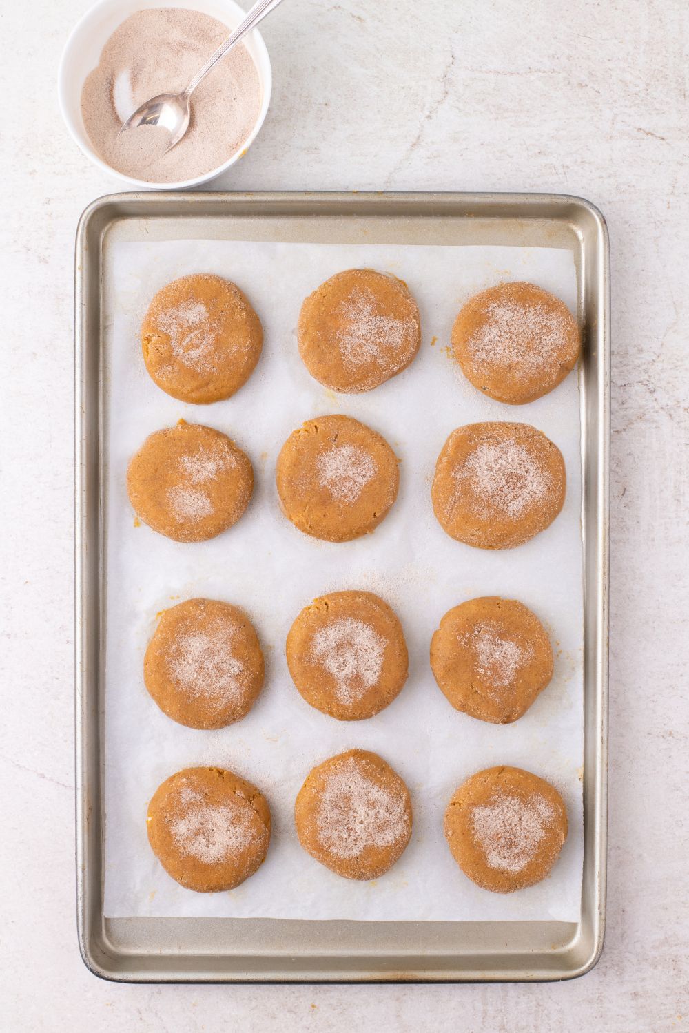 cinnamon sugar coated pumpkin cheesecake stuffed cookies on a baking tray
