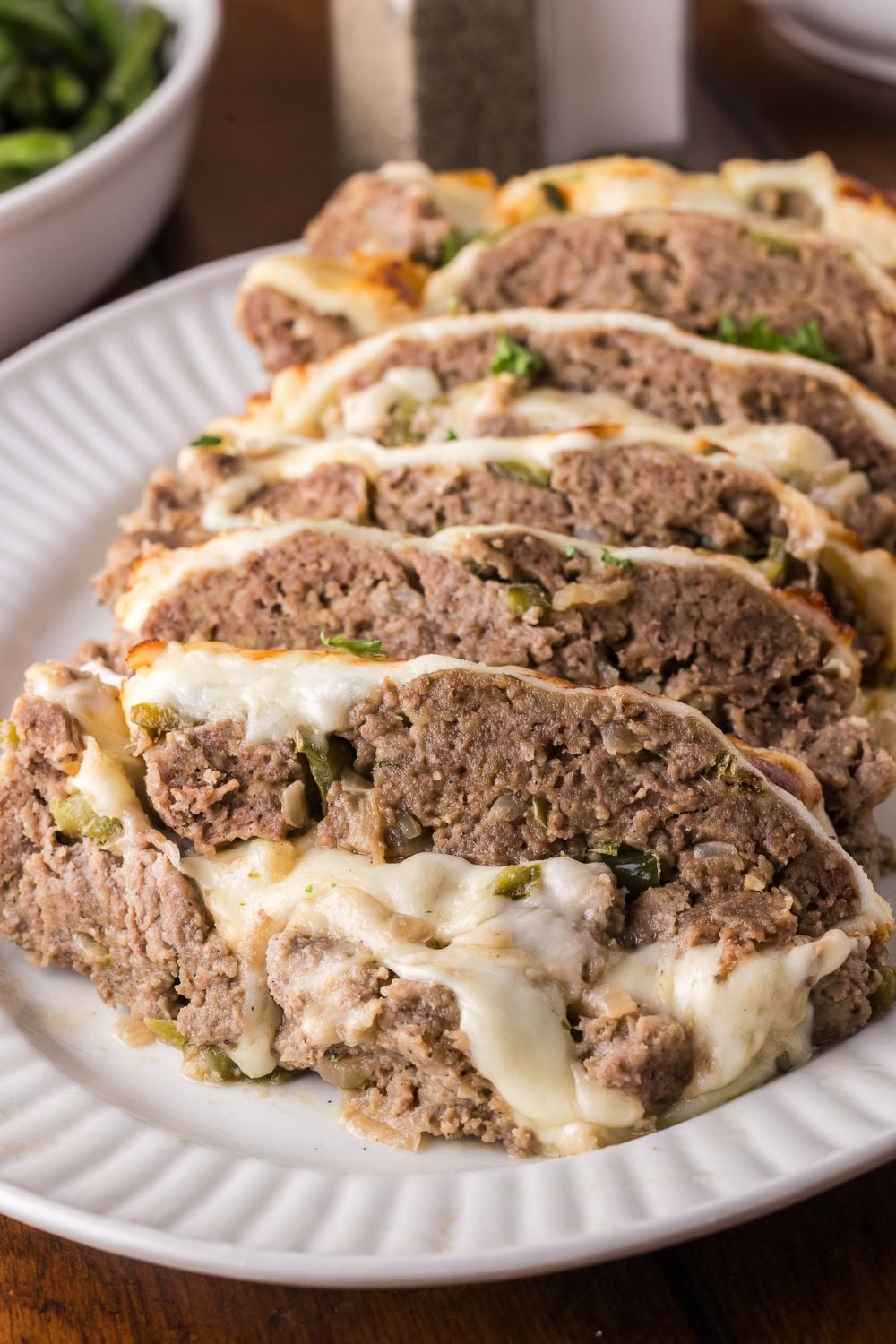 wooden table with a plate full of sliced Stuffed Philly Cheesesteak Meatloaf