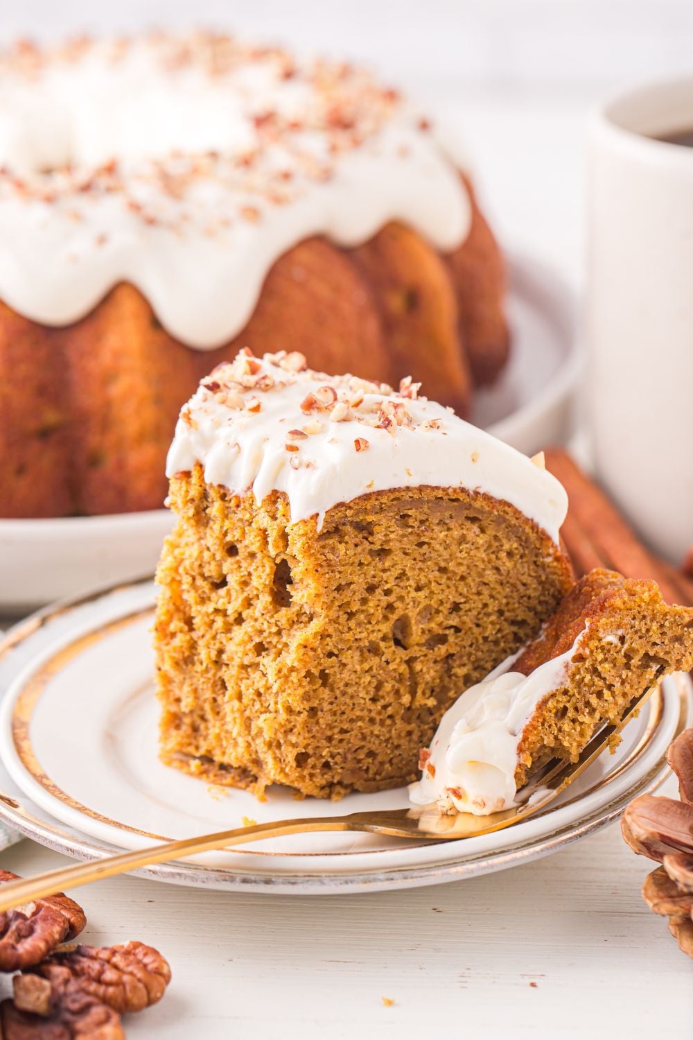 plate with a slice of Pumpkin Bundt Cake on it with a fork with a bite of the cake on it sitting to side