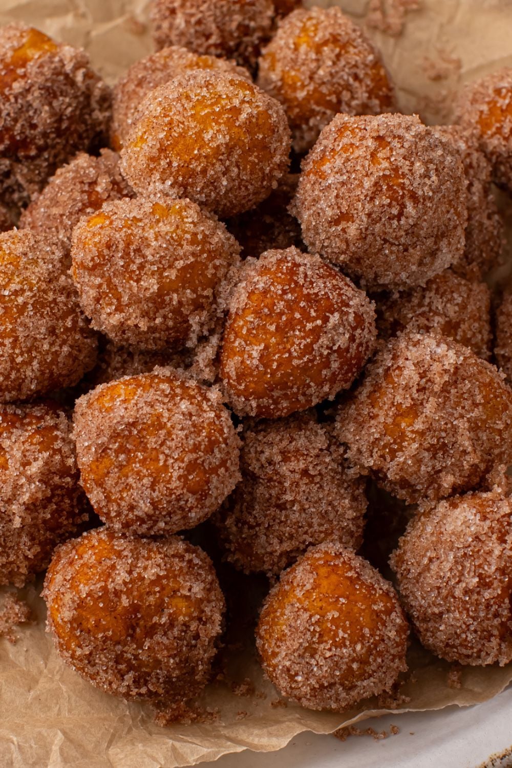 looking down on a wooden table that has a platter full of Pumpkin Pie Donut Holes stacked on top of each other
