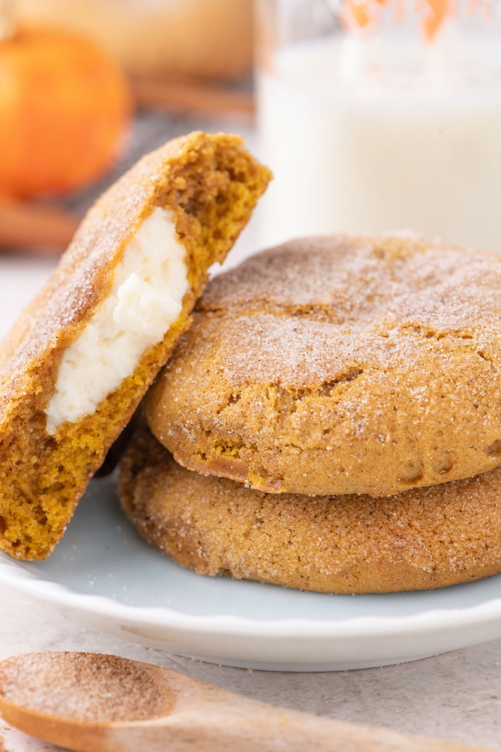 white plate sitting on table with two cookies on plate with one cookie cut in half and placed sideways on plate