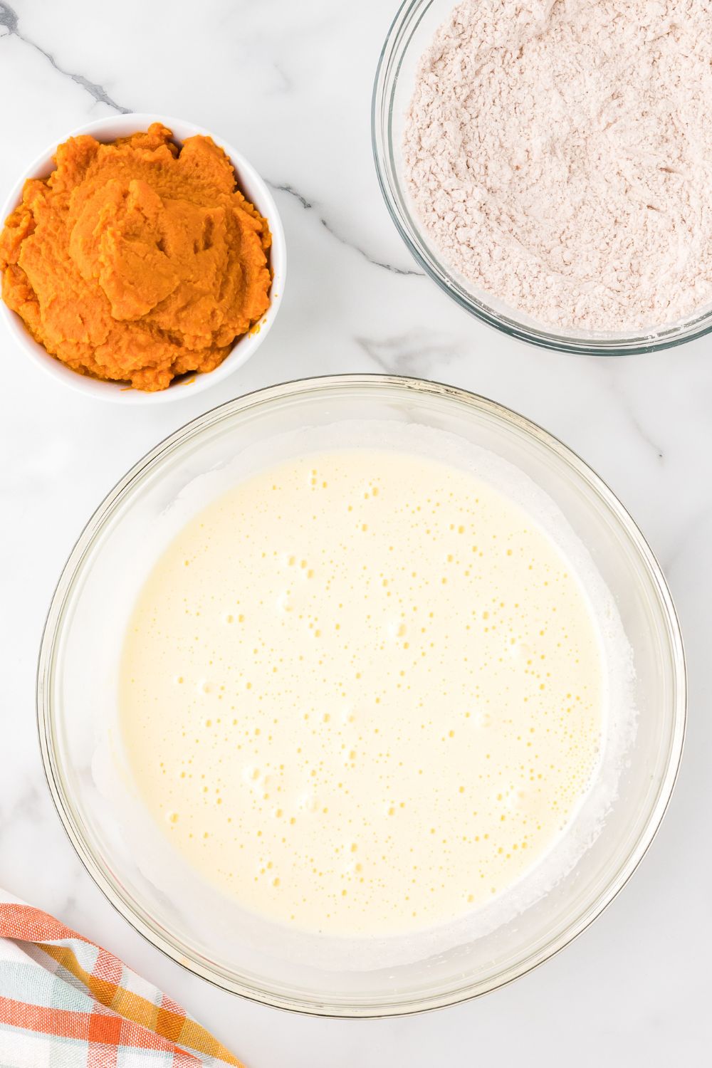 wet ingredients mixed up in a glass bowl on table for making Pumpkin Cake Roll