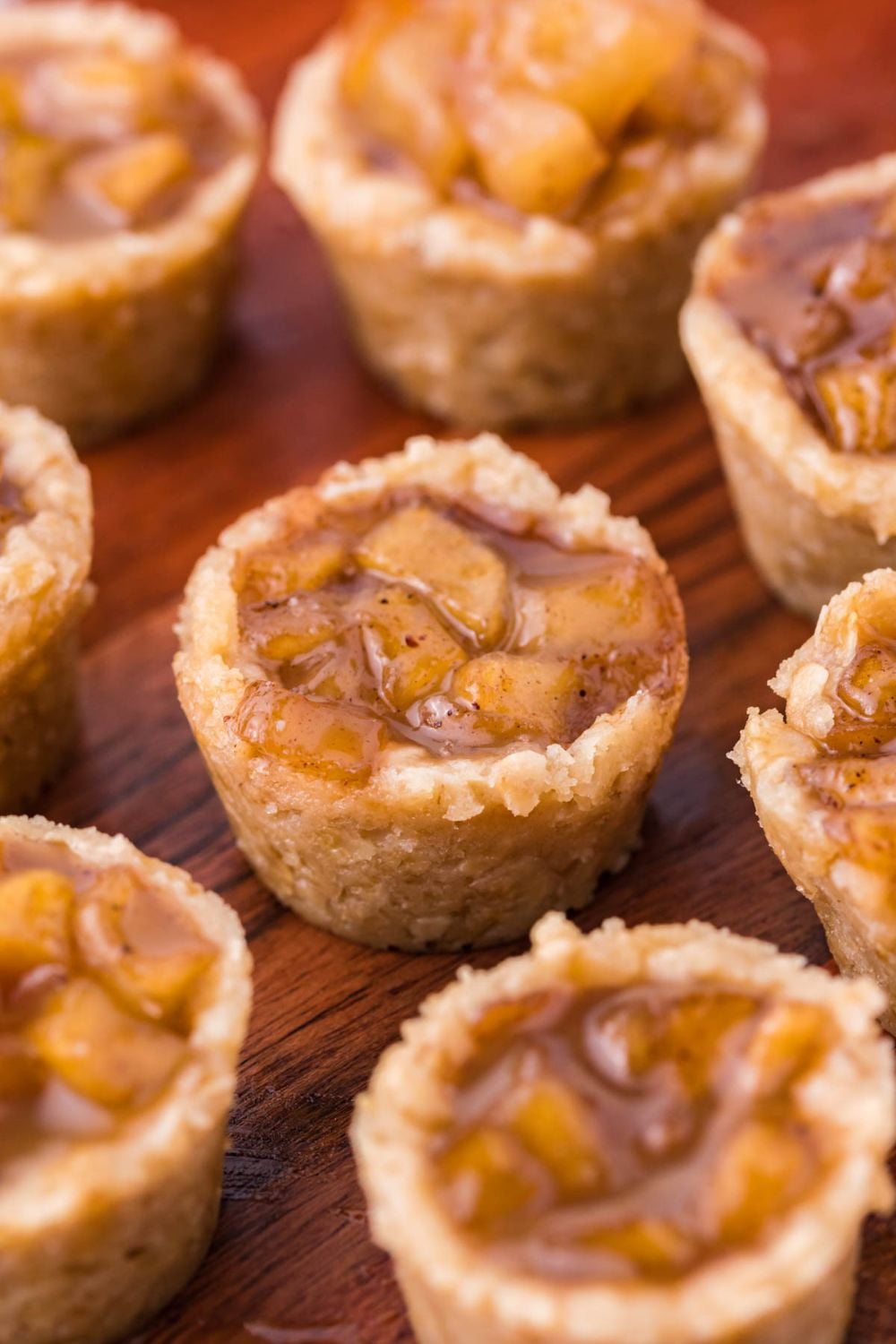 Mini Apple Crisp Bites scattered on a wooden platter on table showing the sweet apple filling and oat base