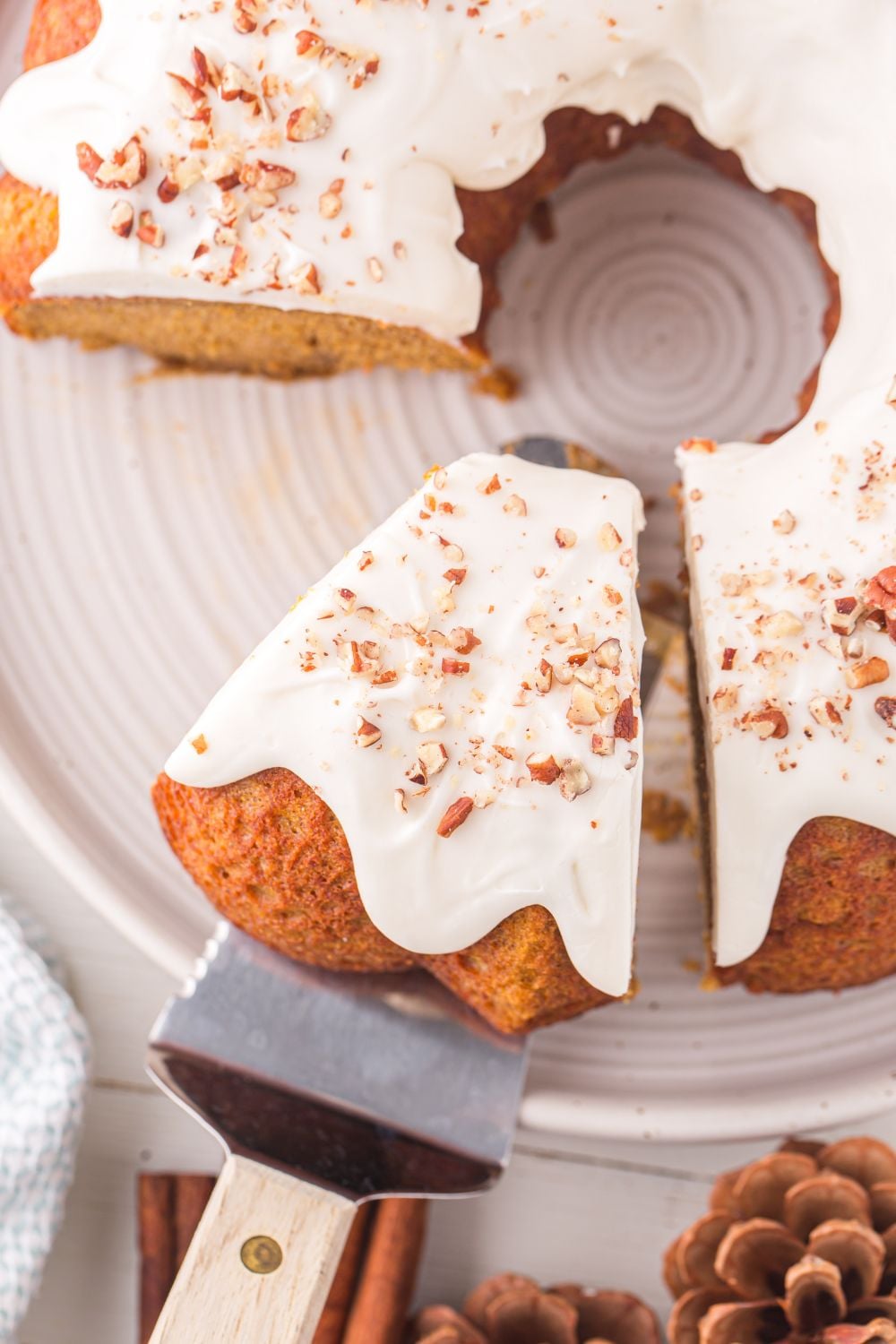 Pumpkin Bundt Cake on a white platter on table with a few slices removed and one cut on a spatula