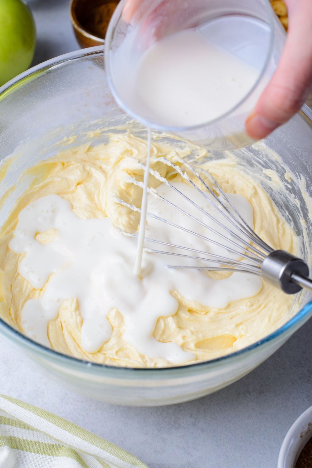 milk mixture pouring into an apple bread batter on table