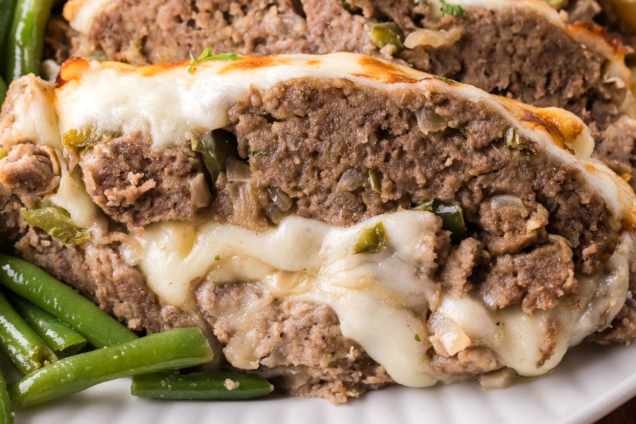 Up close shot of the cheesy inside of the Philly Cheesesteak Meatloaf sliced on a white serving plate