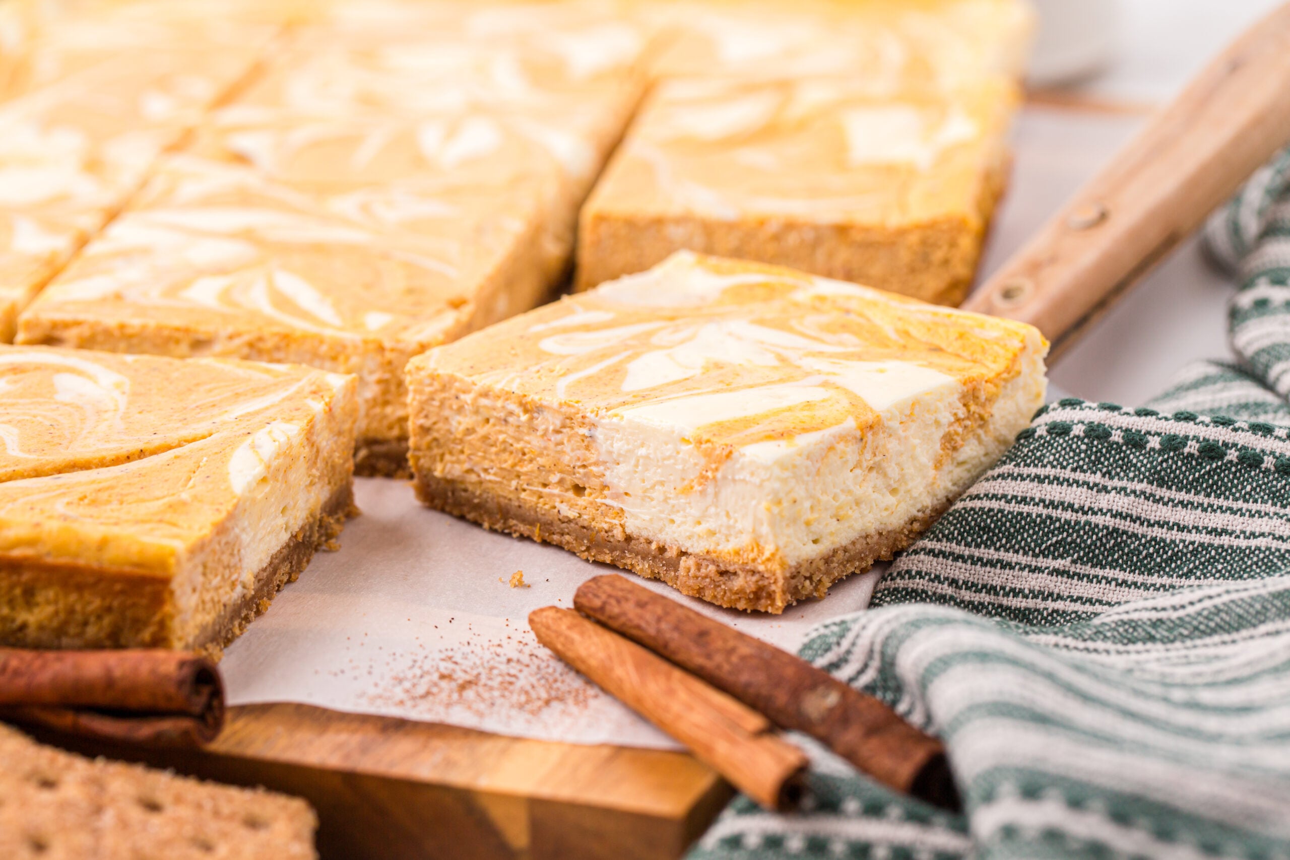 Sliced Swirled Pumpkin Cheesecake Bars placed on a wooden board