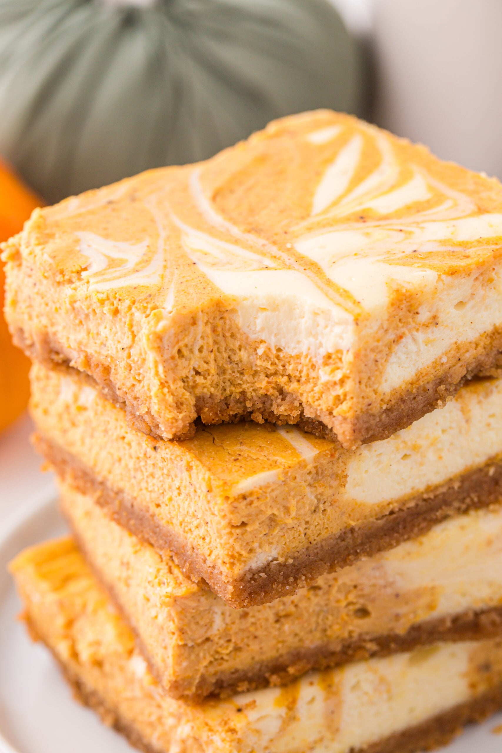 Sliced Swirled Pumpkin Cheesecake Bars stacked with a bite missing from the top one