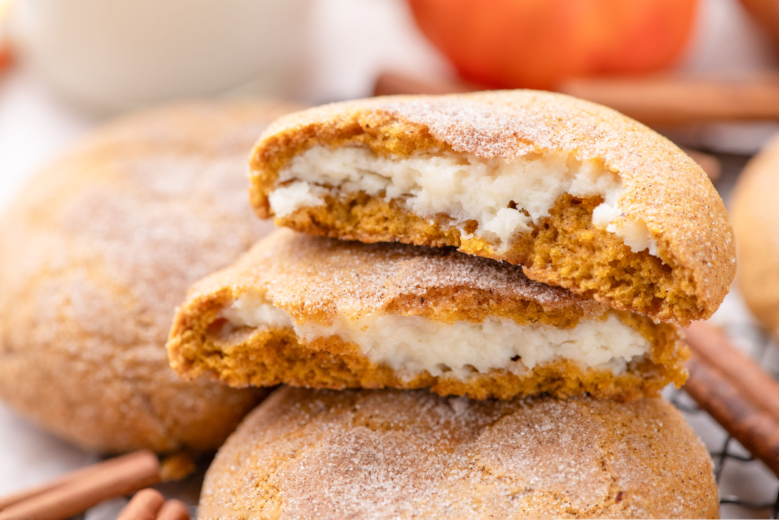 Pumpkin Cheesecake Cookies stacked on a cooling rack with one cut open