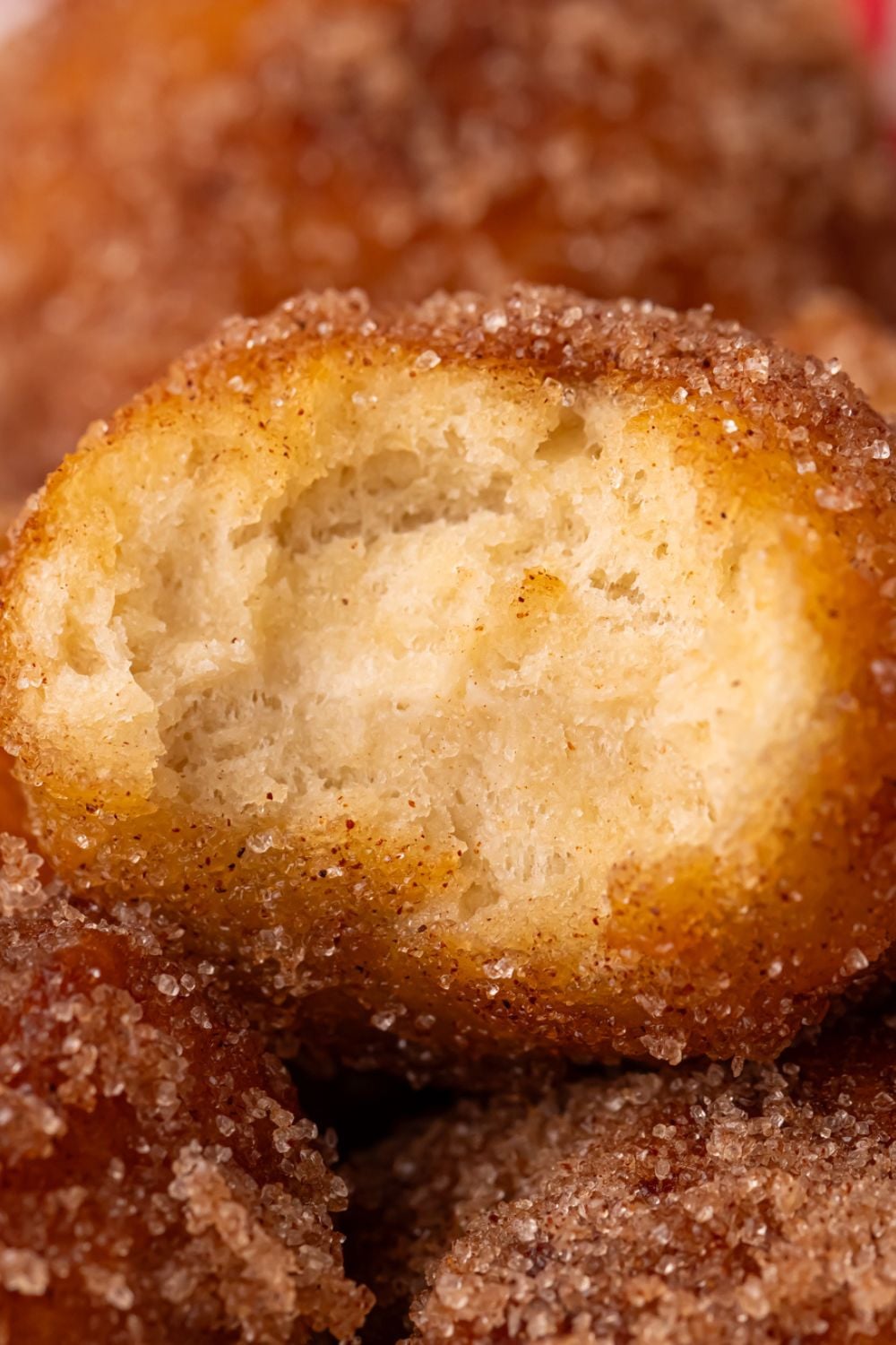 a bite taken out of an Apple Pie Donut Hole that is showing a close up view to show how fluffy it is 