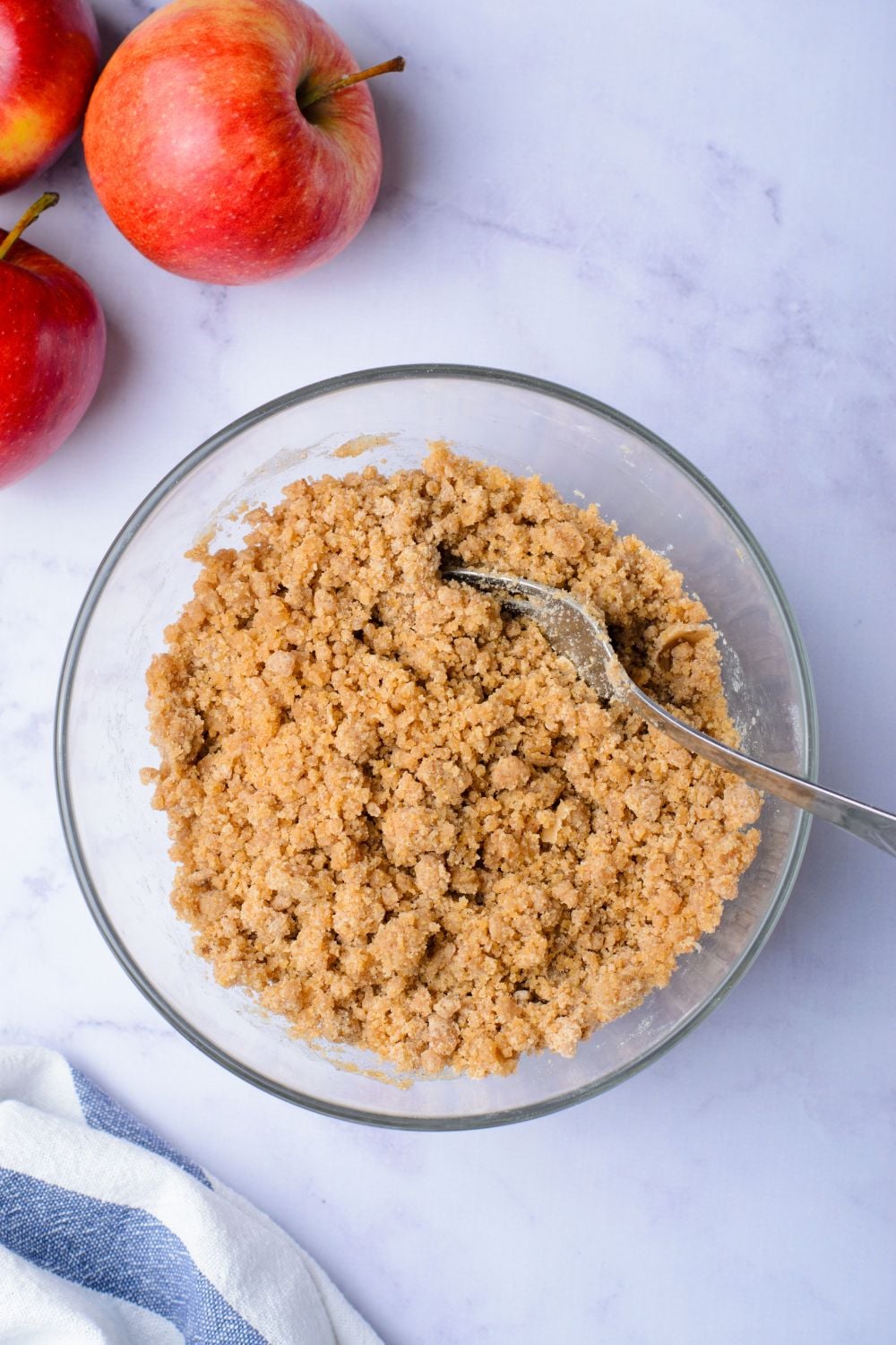 cinnamon sugar mixture in a glass bowl on table with two apples to the side