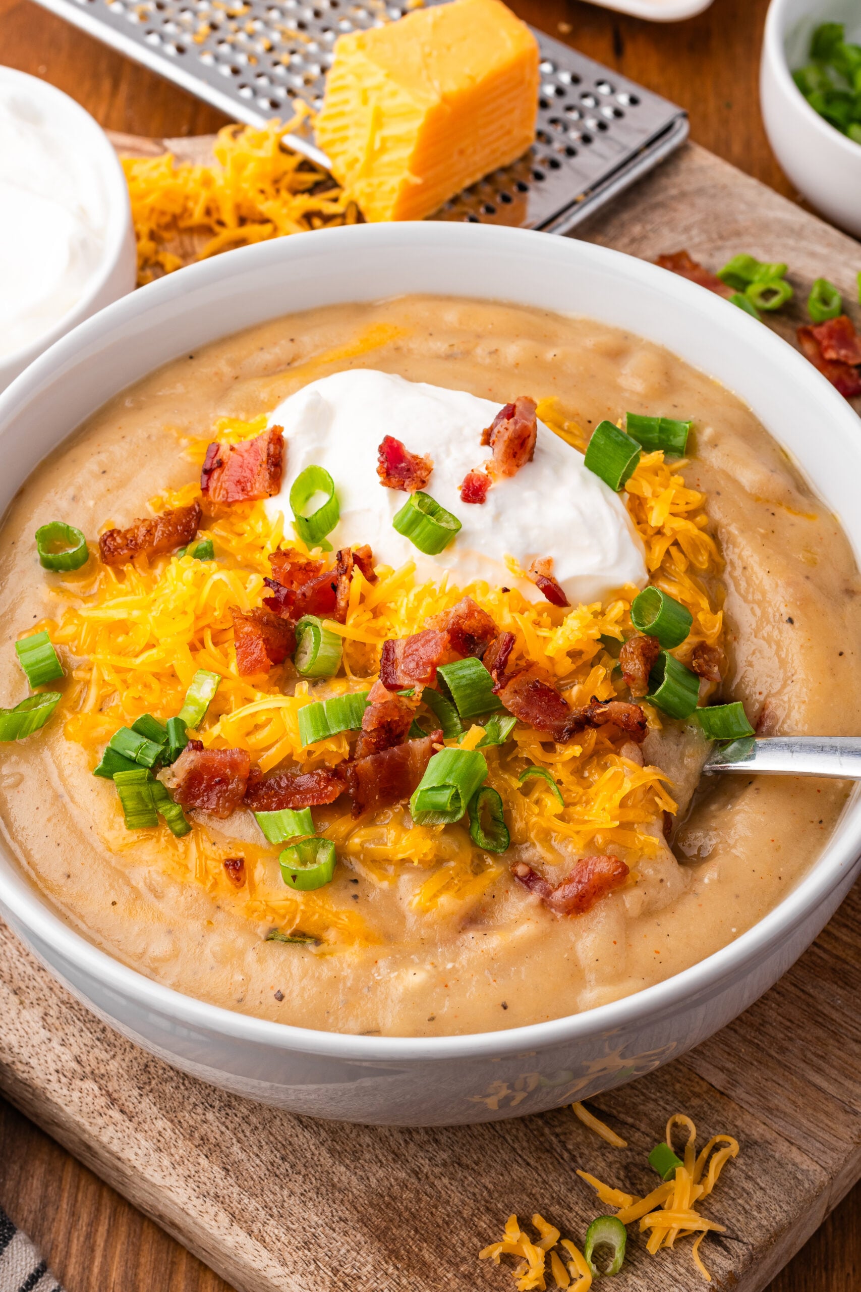 up close shot of the Crock pot loaded baked potato soup in a white bowl topped with bacon, cheese and sour cream