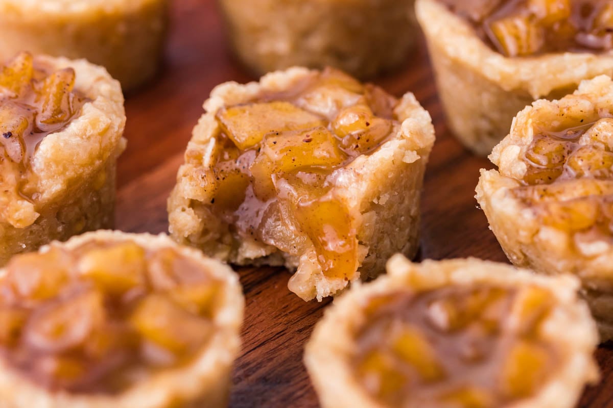 Mini Apple Crisp Bites on a wooden table with the center one missing a bite