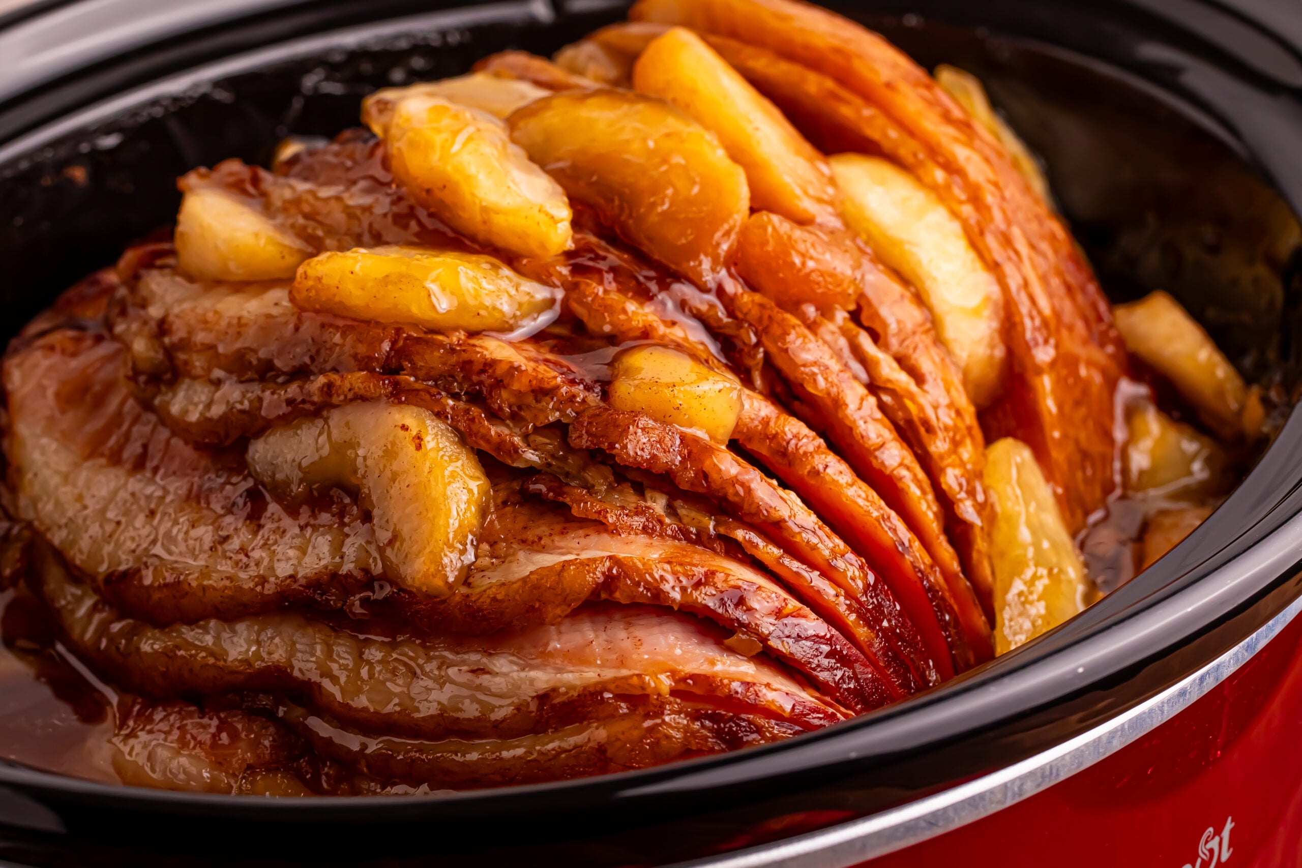 Side view of the Slow Cooker Apple Glazed Ham in a red slow cooker 