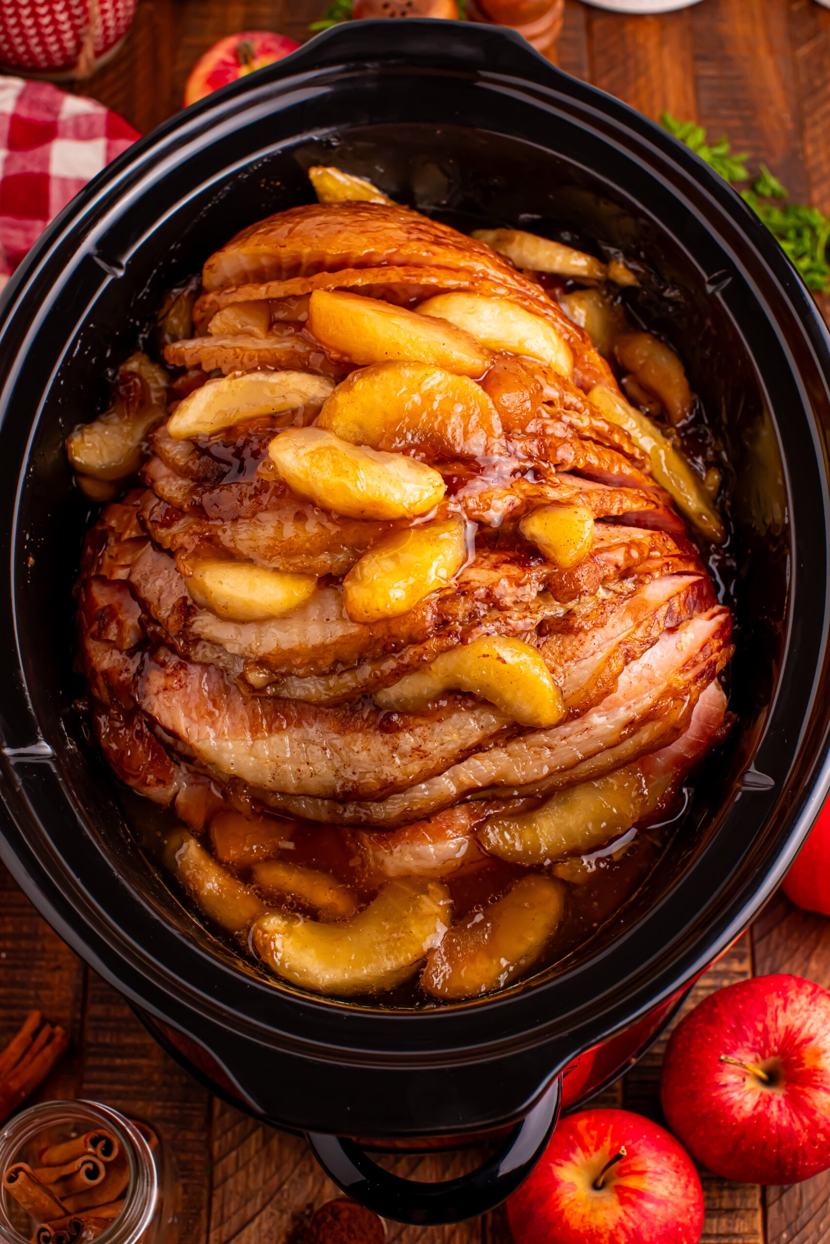 overhead shot of the cooked Slow Cooker Apple Glazed Ham in a black crock pot on a dark wood table 