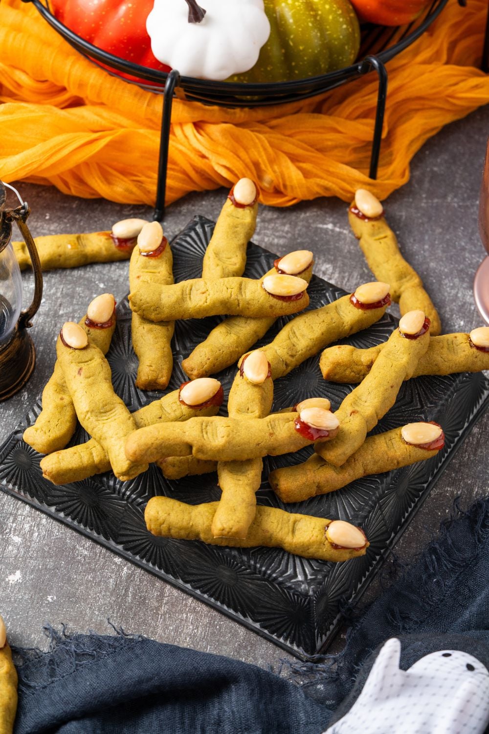 A Halloween decorated table with a tray full of green Witch Finger Cookies as the center of the picture