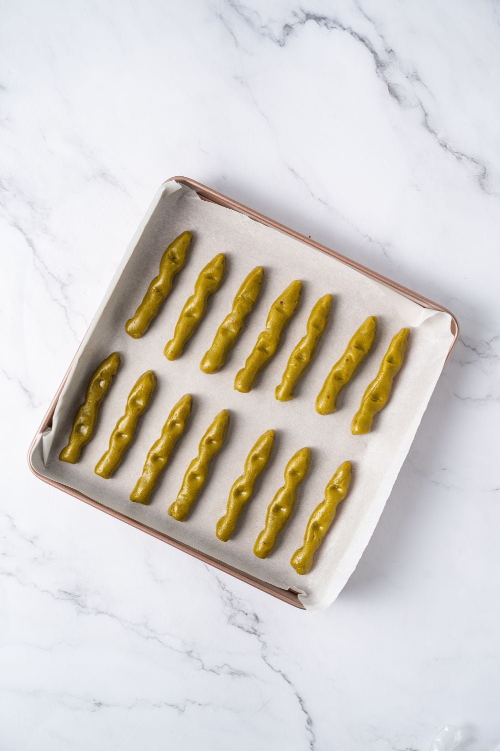 Witch Finger Cookie dough in strips on a baking dish with parchment paper