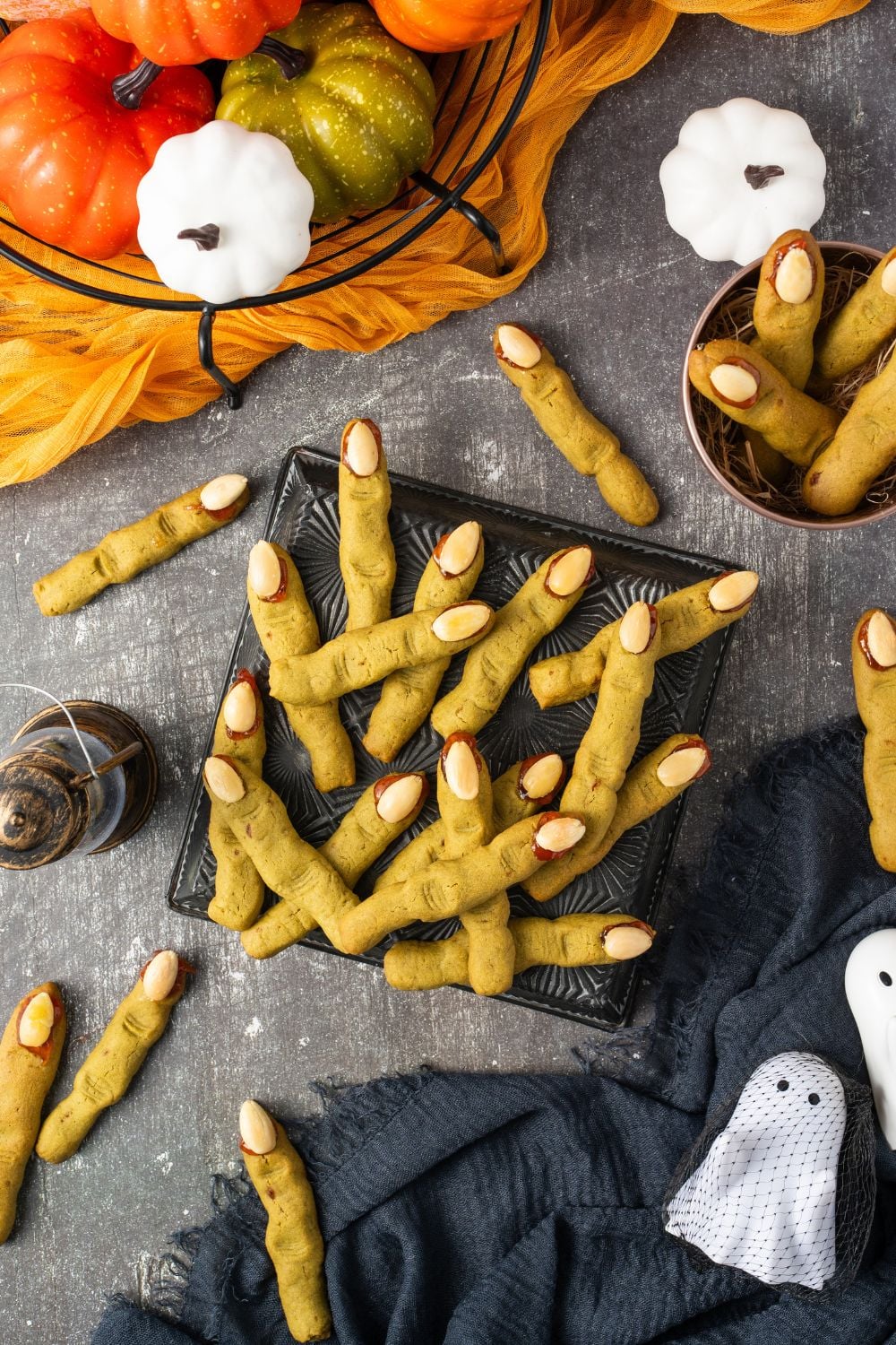 Witch Finger Cookies in a square plate on table with more scattered around the table with Halloween decor all around table
