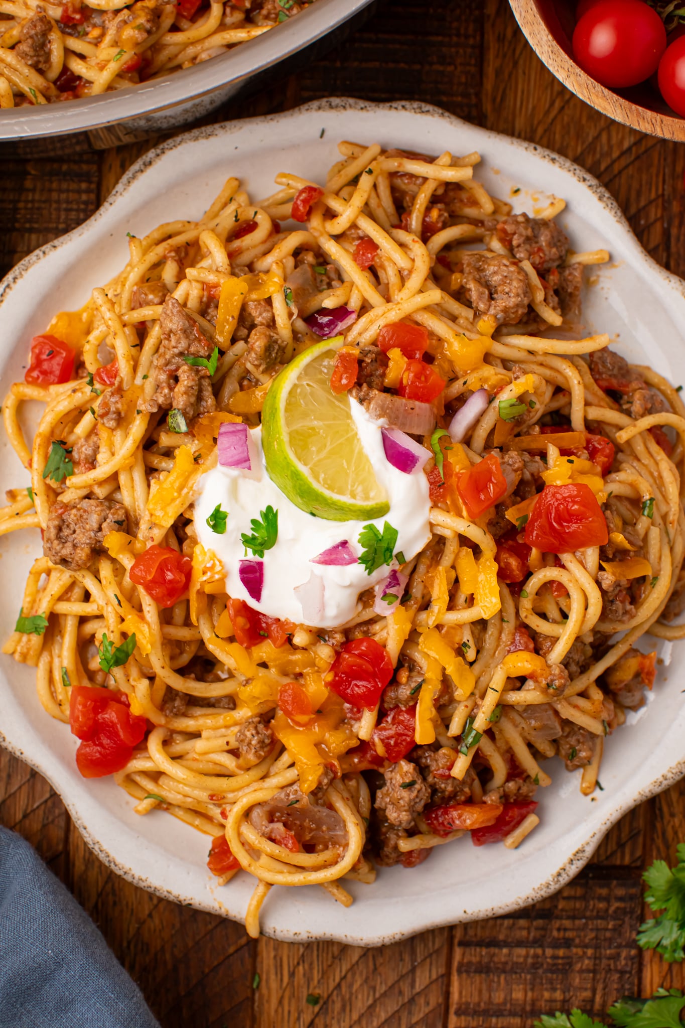 Plate of Cheesy Taco Spaghetti topped with sour cream and lime