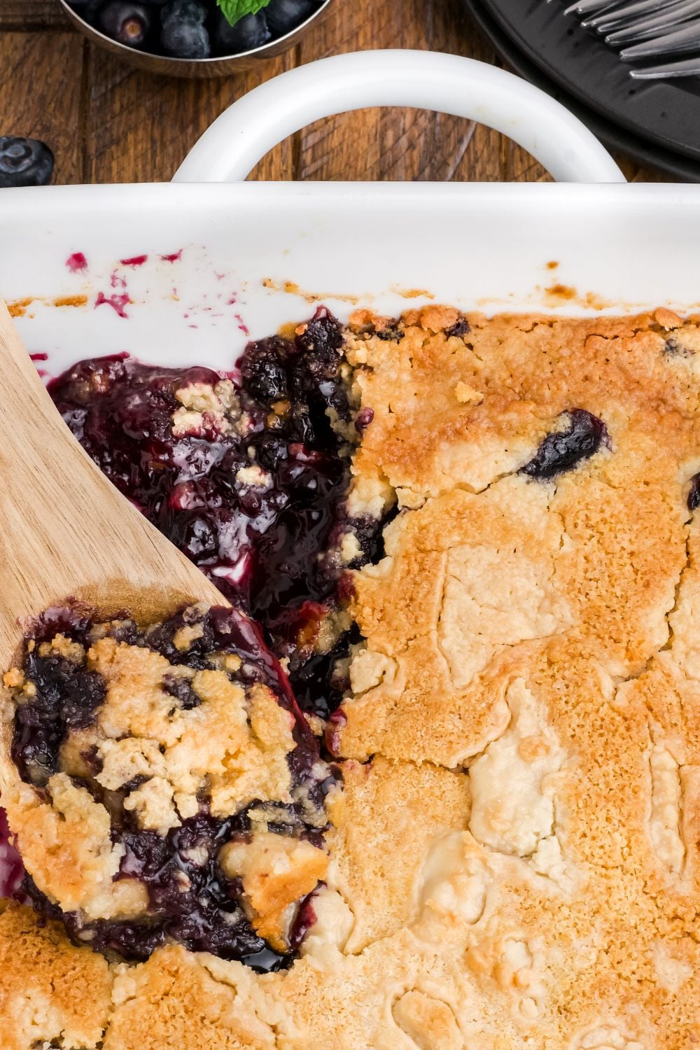 Blueberry Dump Cake in a pan with a wooden spoon scooping some up