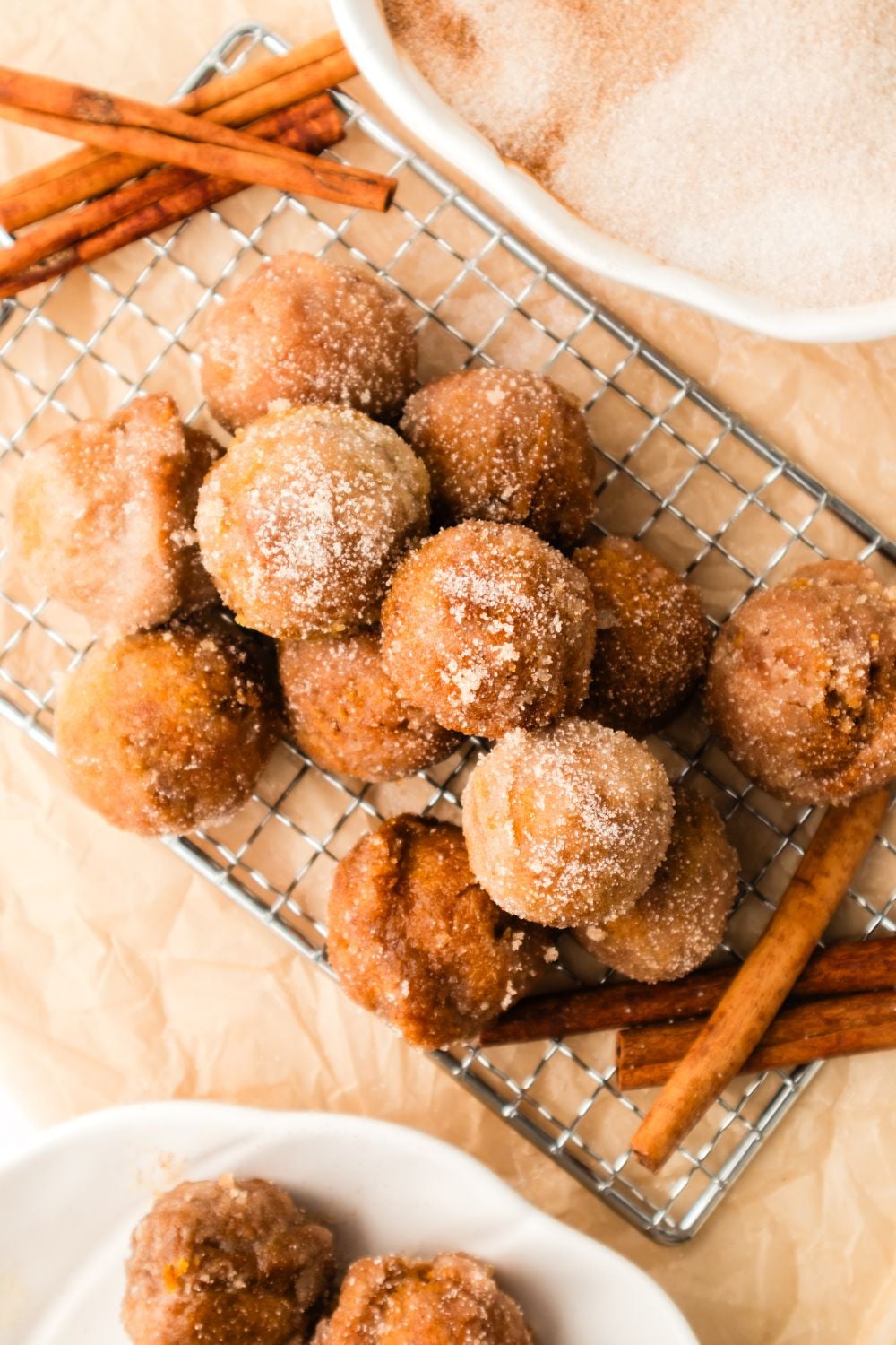 Pumpkin Spice Donut Holes on a metal tray with a few cinnamon sticks to the side 