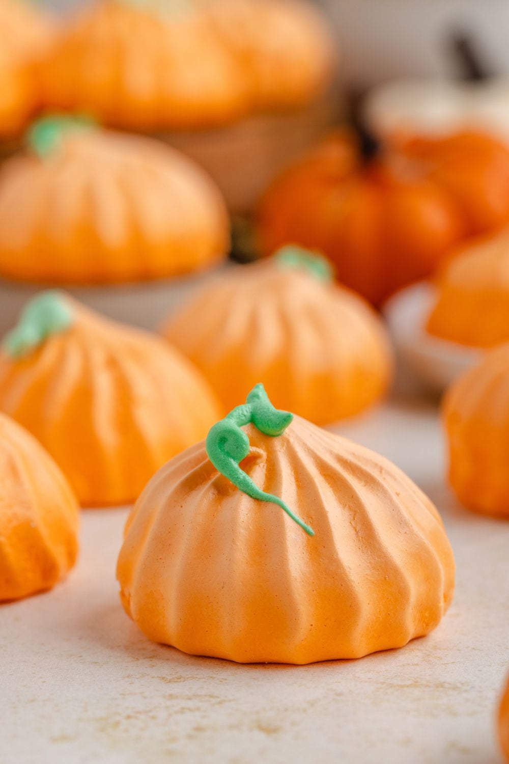 Pumpkin Meringues placed around table in a single row with faux mini pumpkins on table as well 