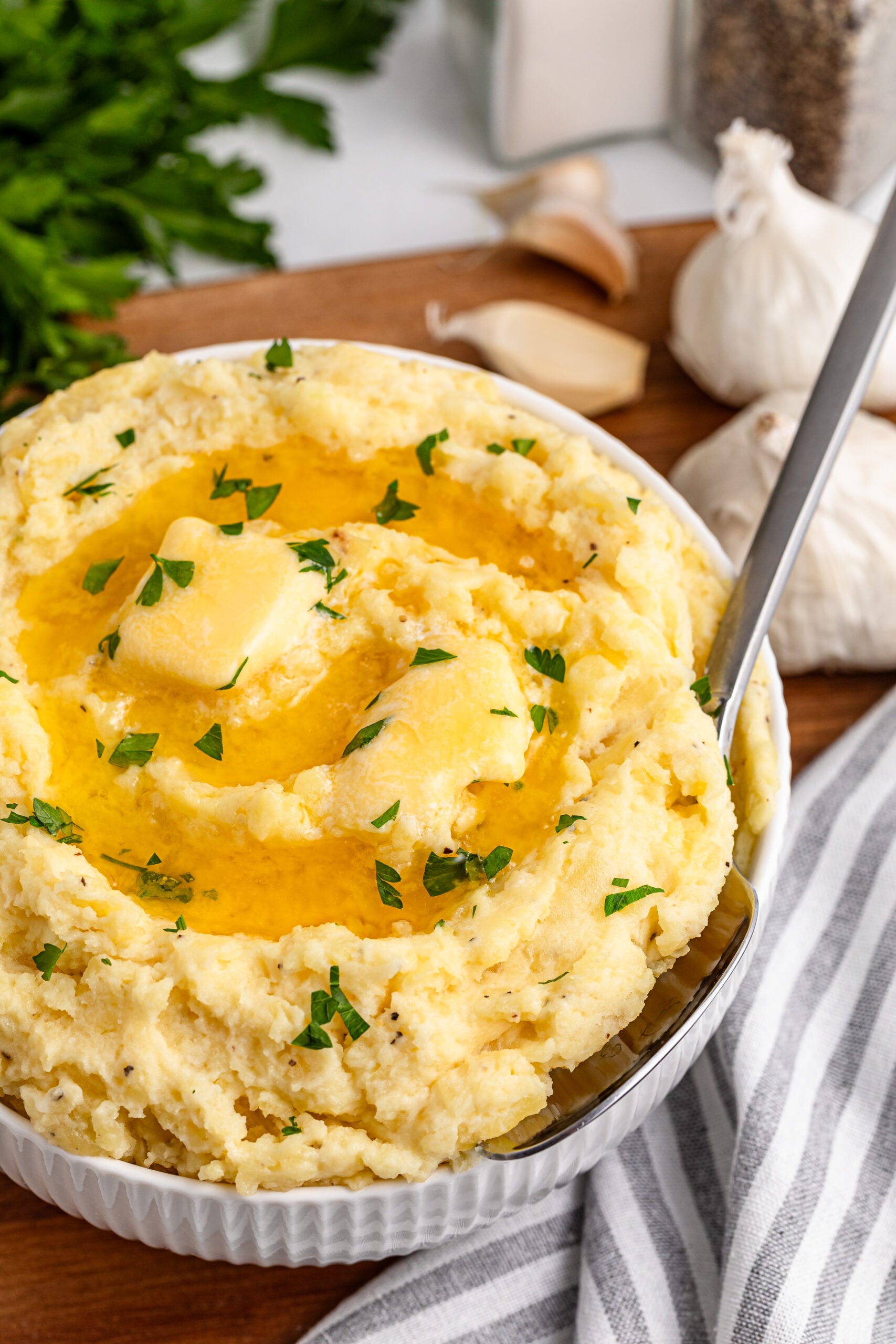 Garlic mashed potatoes in a white bowl on a dark wood table