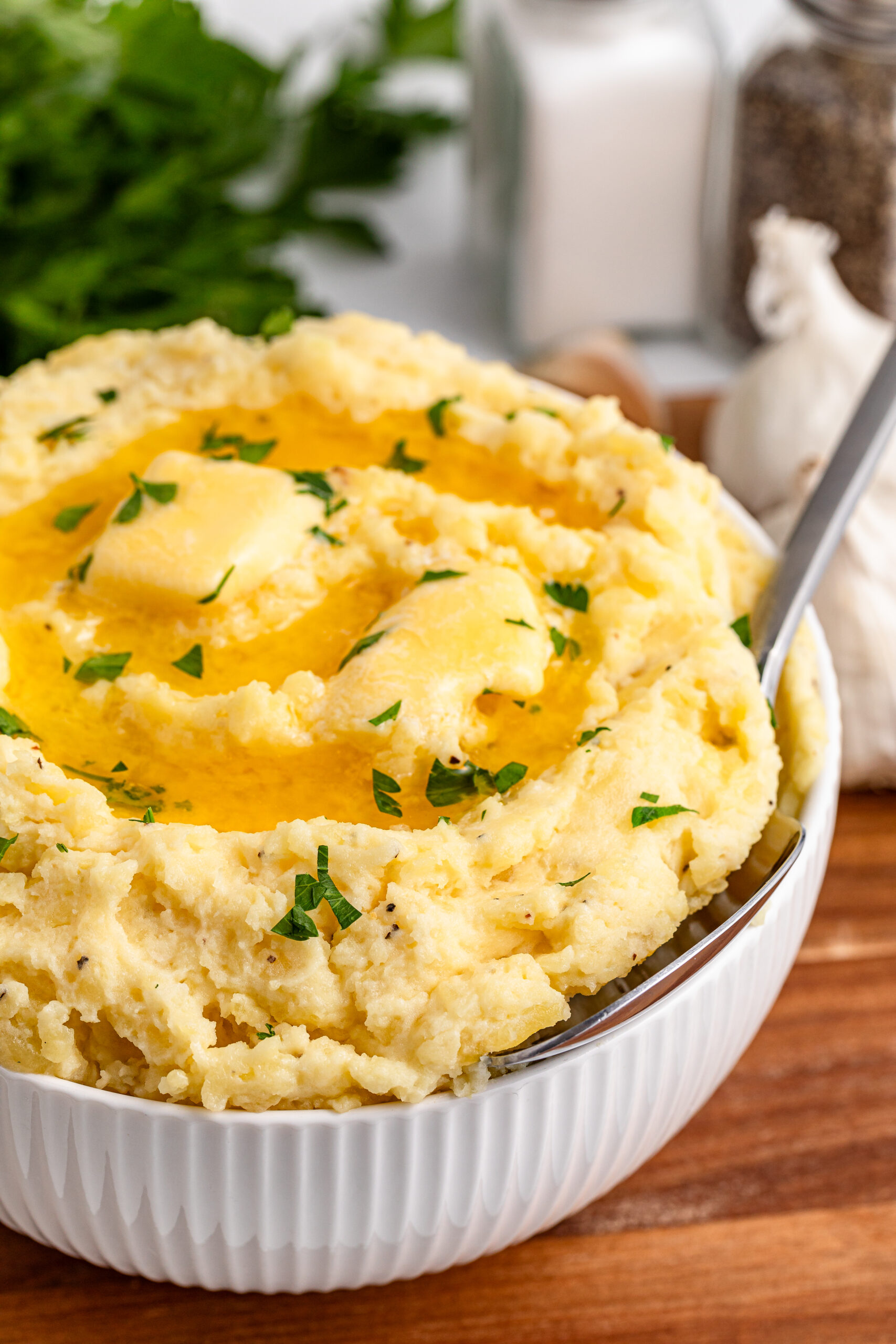 Garlic mashed potatoes in a white bowl on a dark wood table