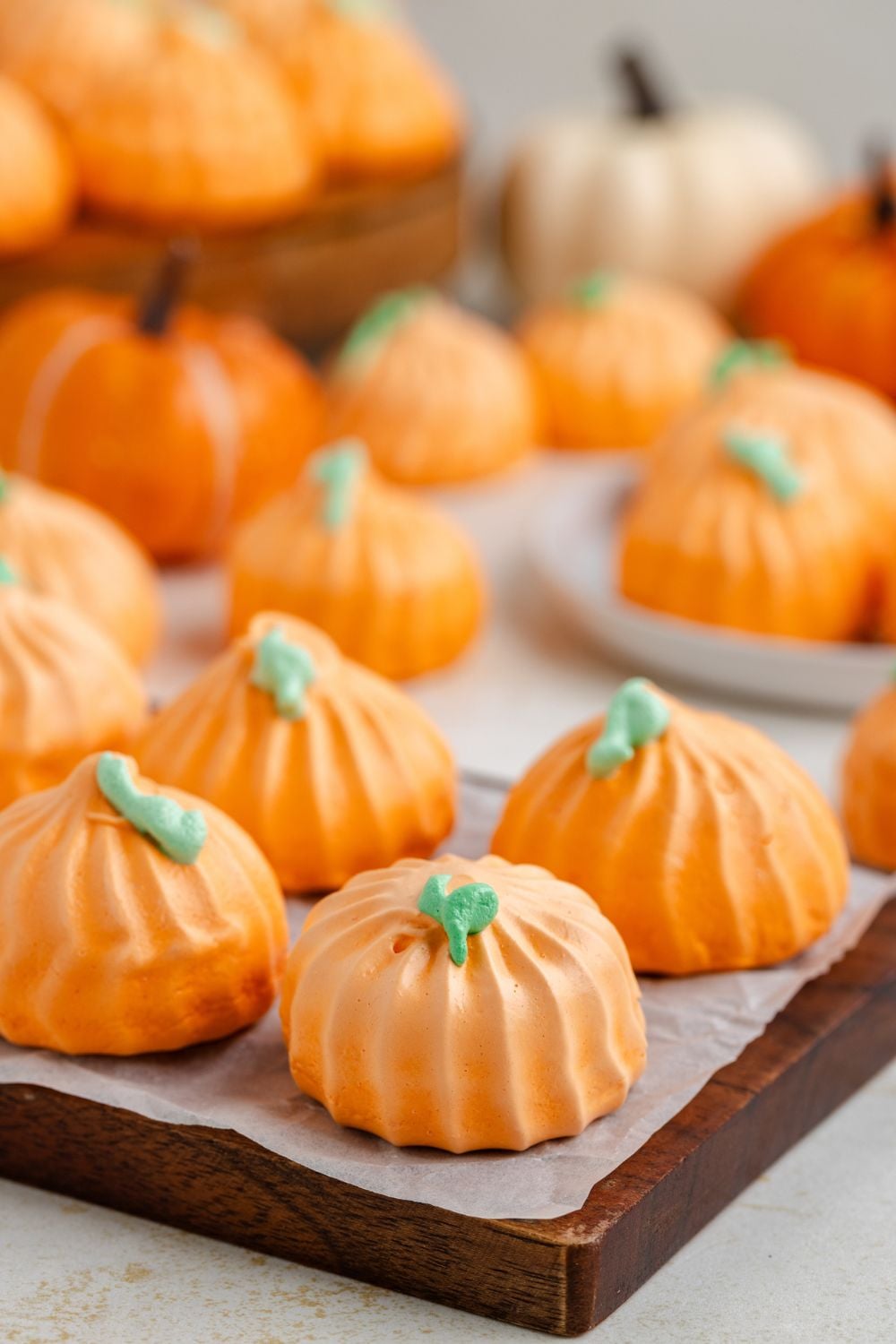 wooden serving tray with some Pumpkin Meringues placed on it, and more scattered around the table on plates and on trays 